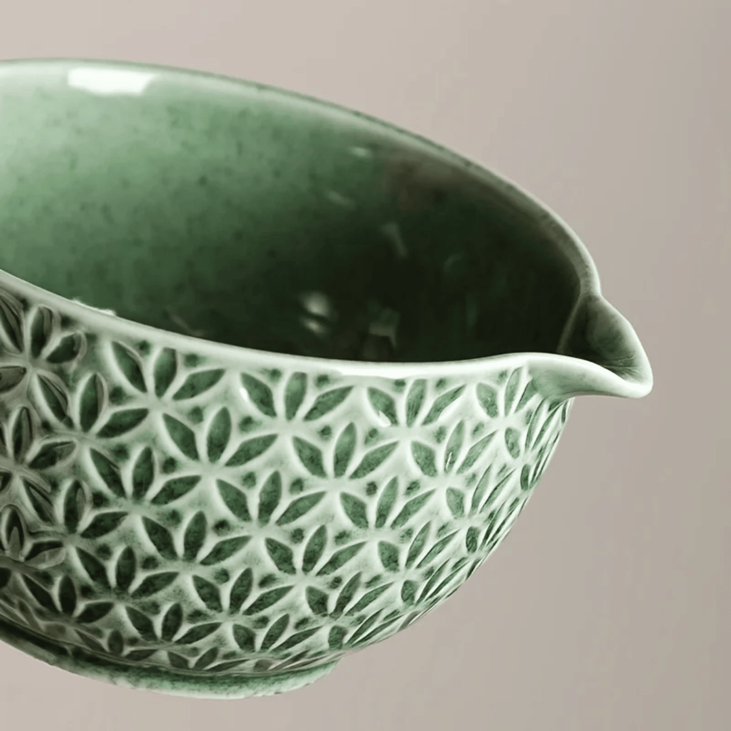 Green ceramic bowl with a geometric pattern on a beige background