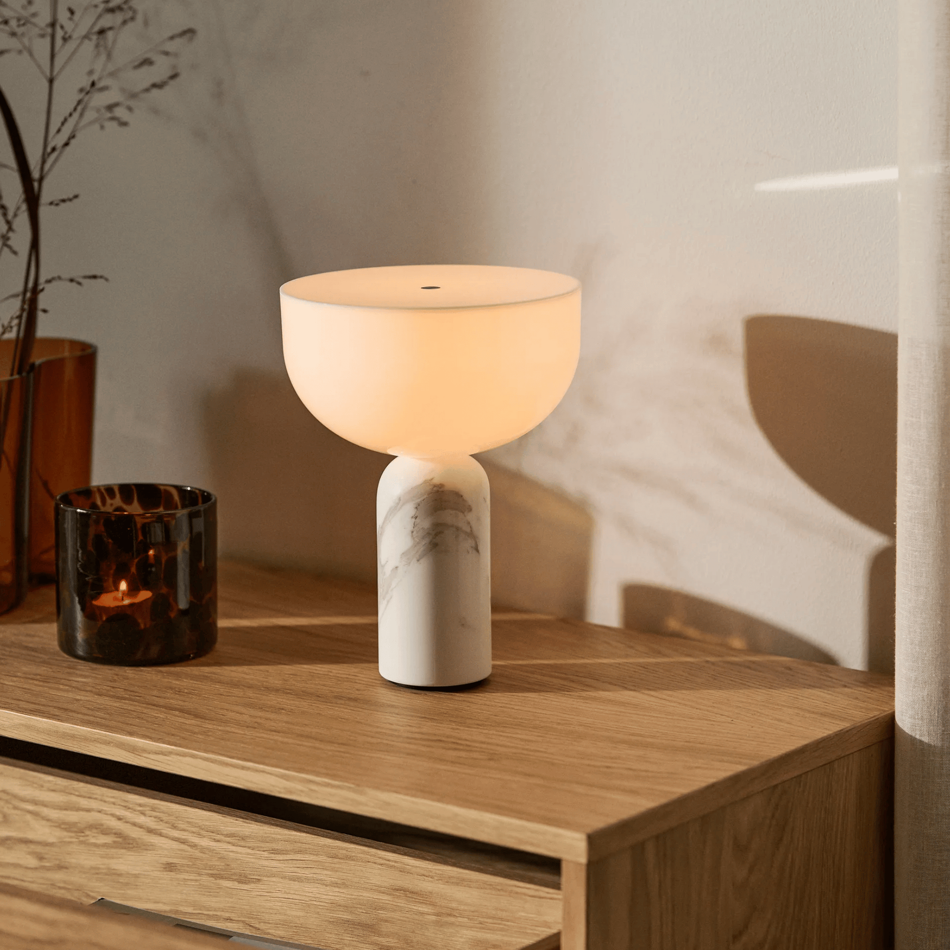 Table lamp with marble base on a wooden surface next to a candle