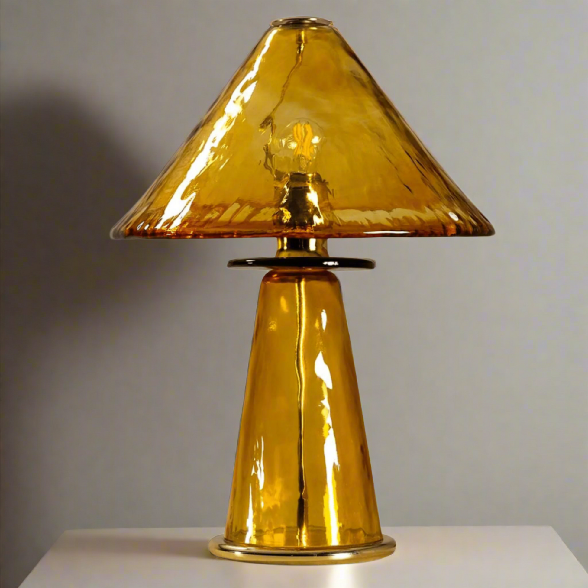 Gold table lamp with a yellowish-brown glass shade on a white background