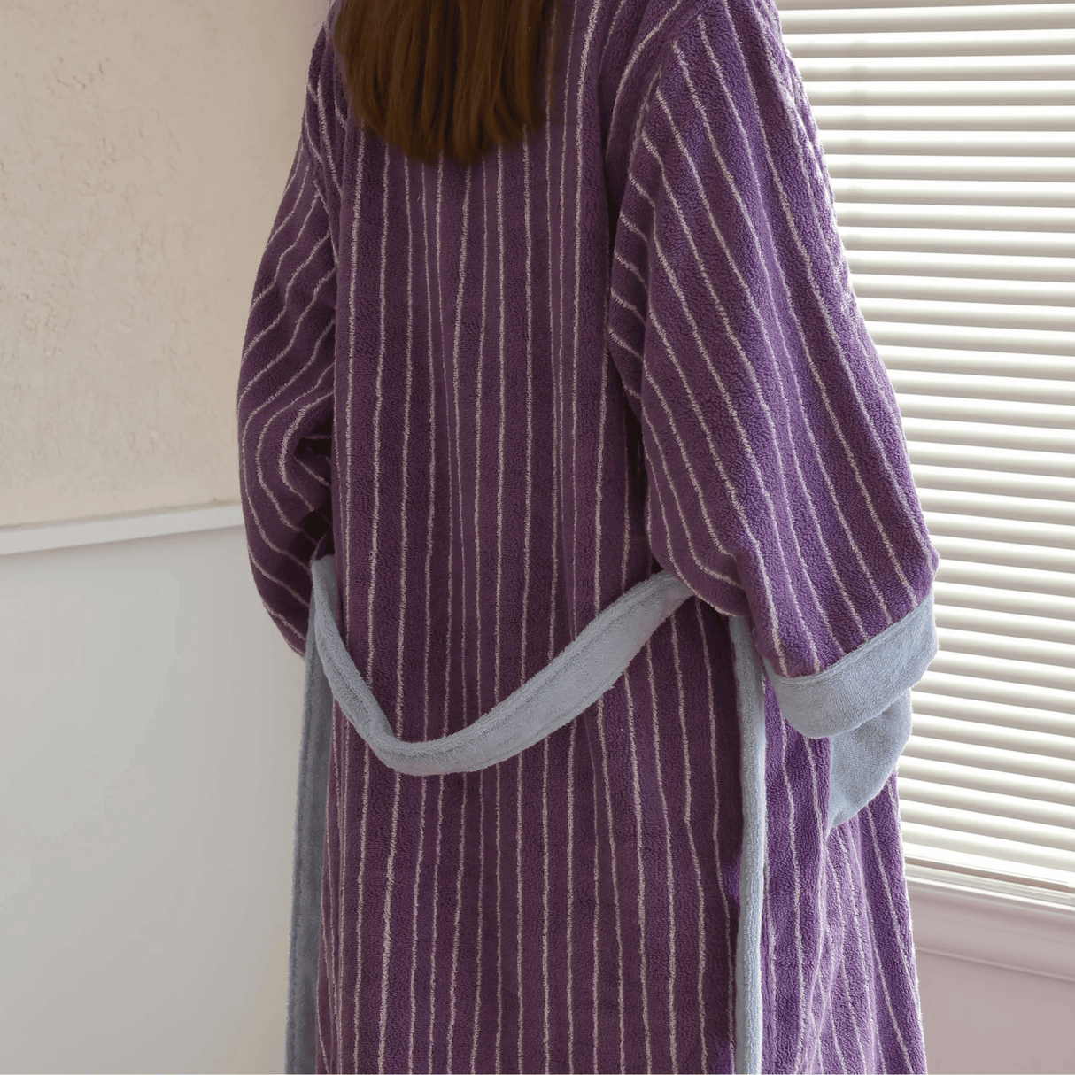 Person wearing a purple striped robe with gray trim indoors.