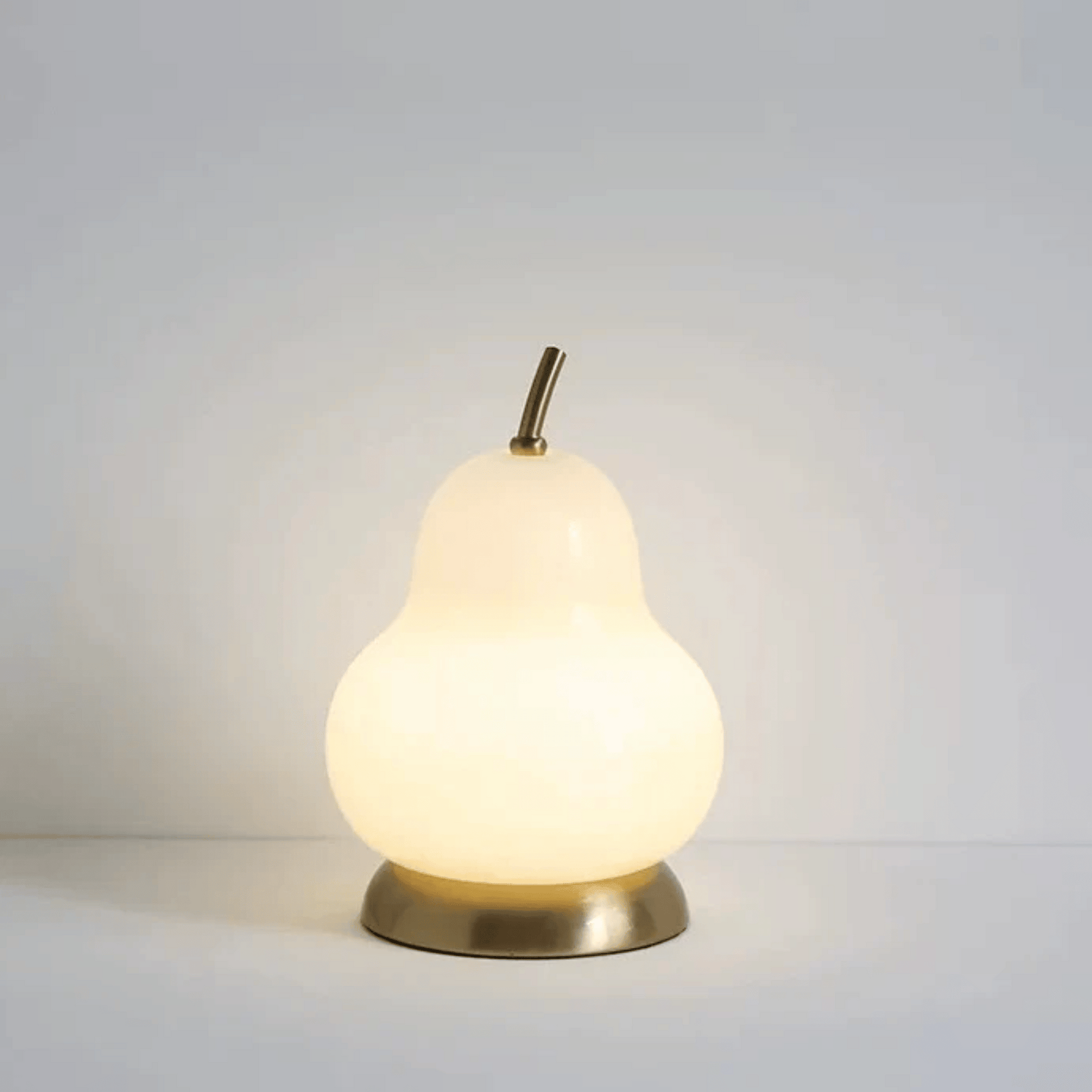 Pear-shaped lamp with a gold base on a light gray background