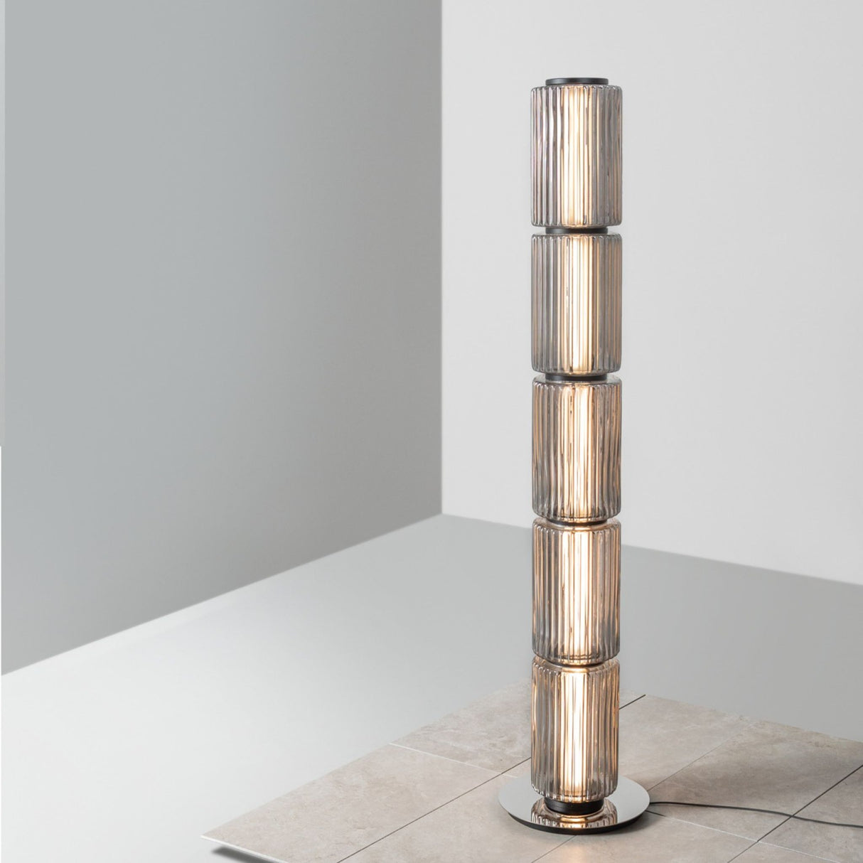 Ribbed-glass floor lamp placed beside long gray curtains near a seating area.