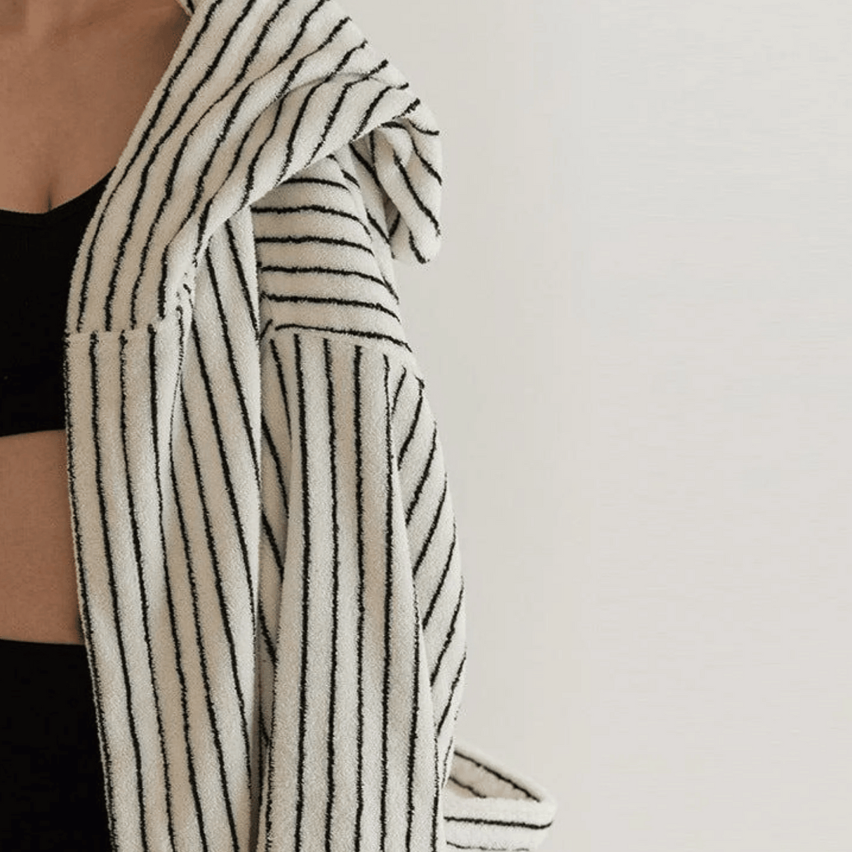 Person wearing a black and white striped robe against a plain background