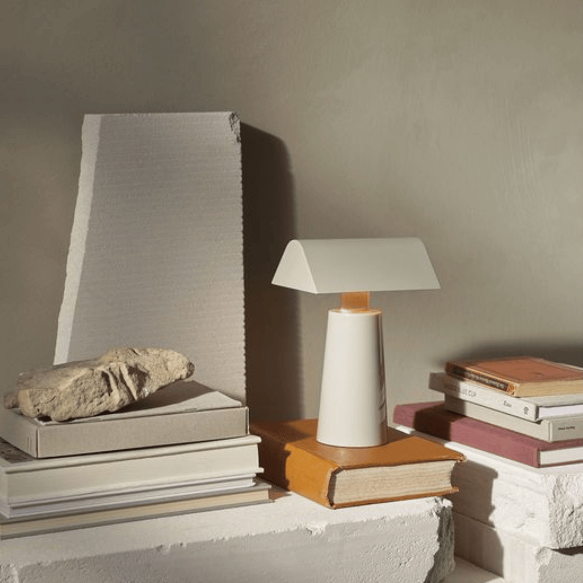 Table lamp on a stack of books with a textured wall background