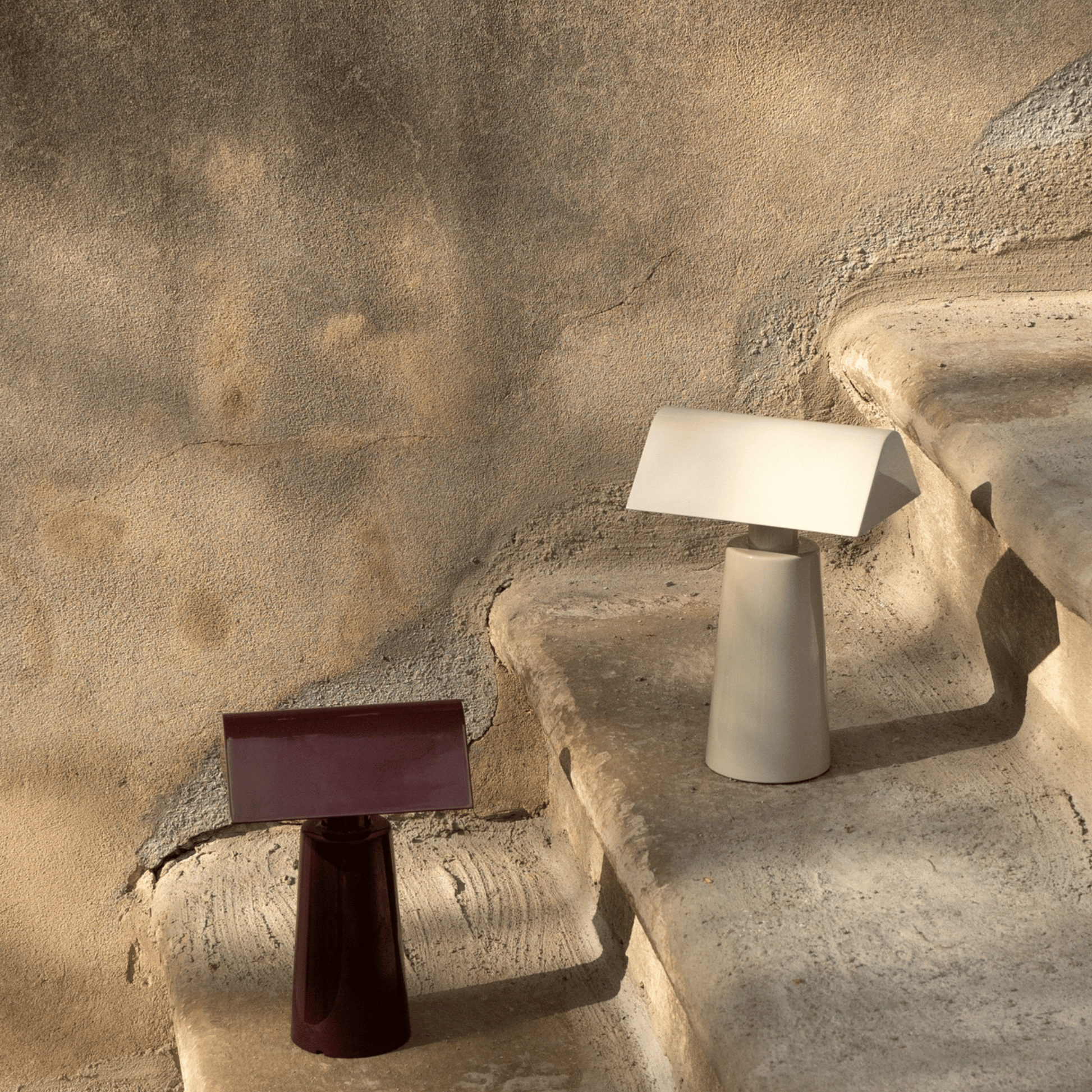 Two modern table lamps on a textured stone surface