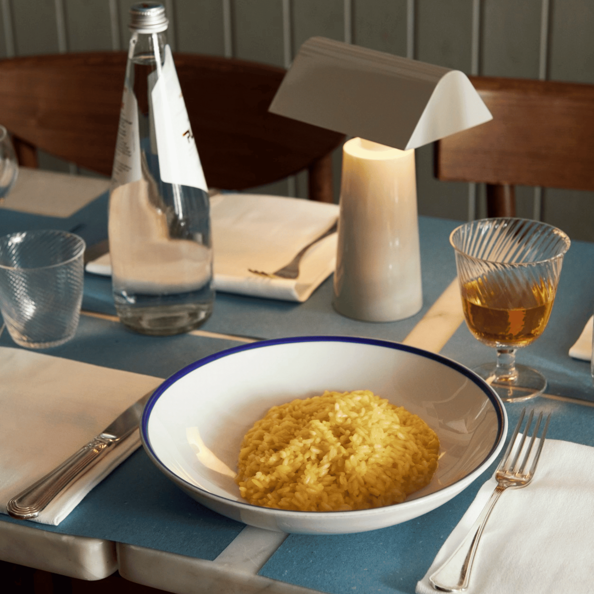 Dinner table setting with a bowl of food, water bottle, and candle.