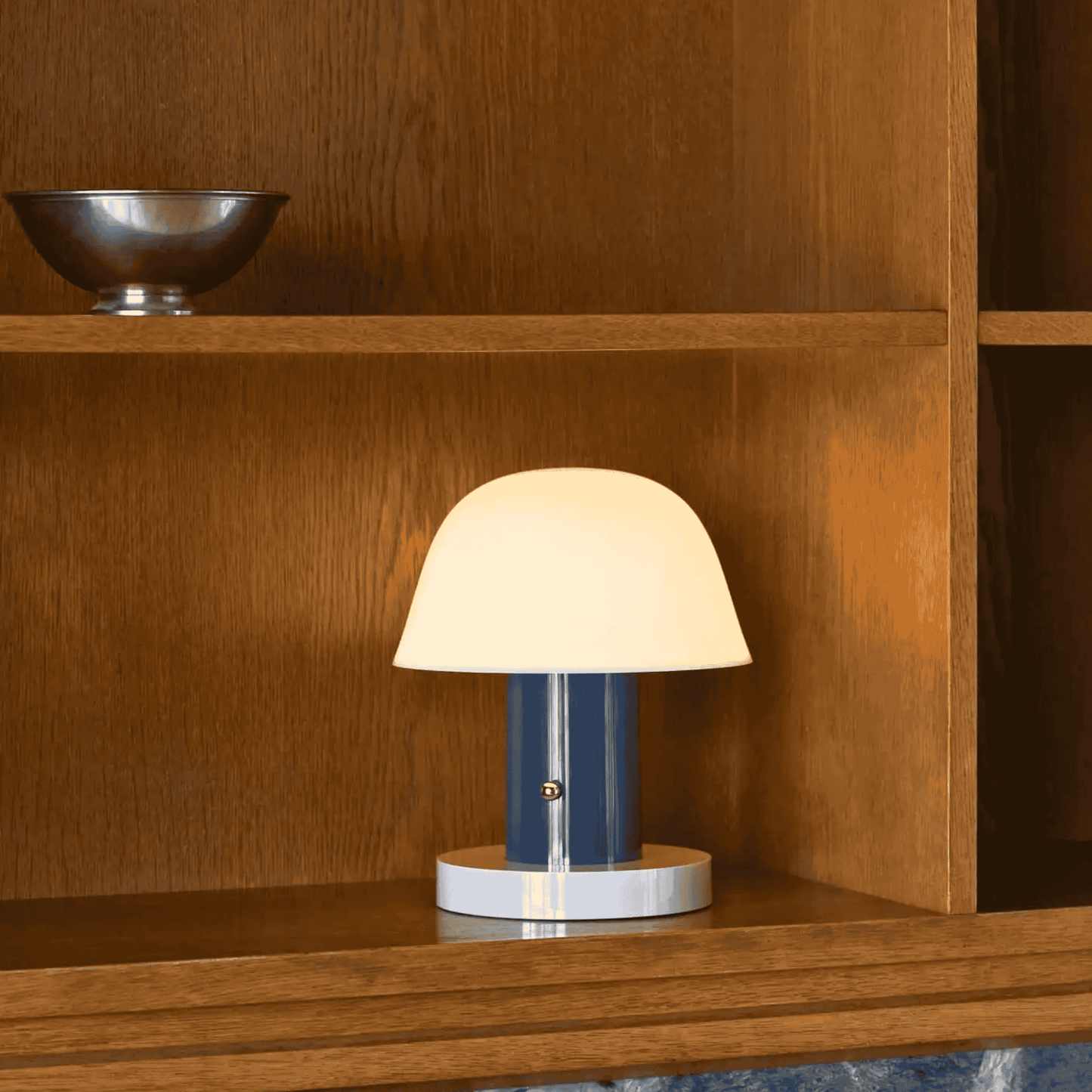 Small lamp on a wooden shelf with a bowl in the background