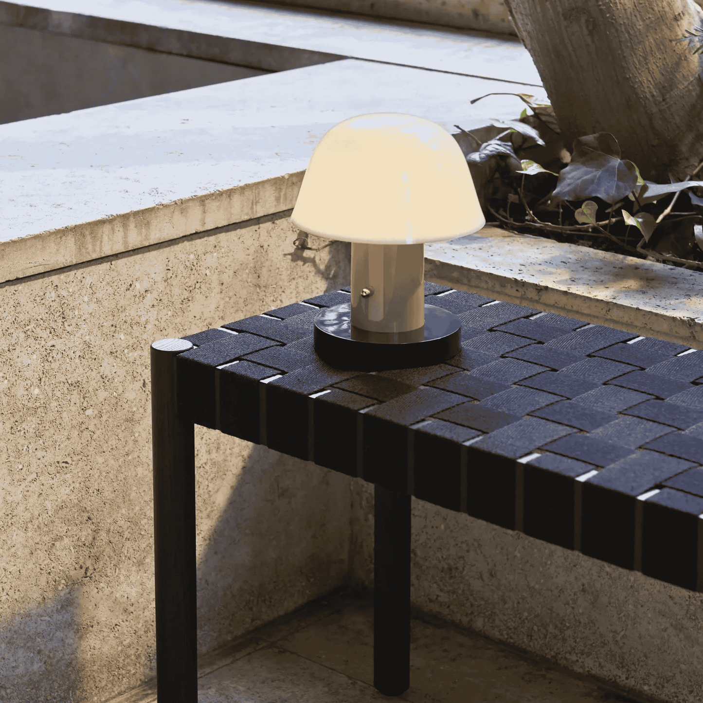 Small table lamp on a black tiled table outdoors.