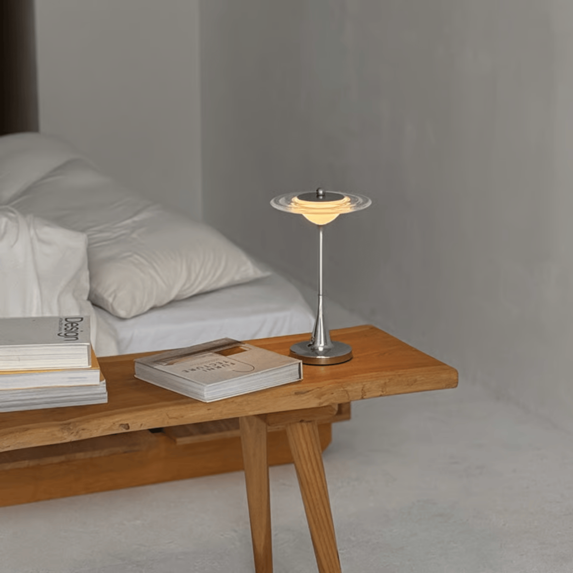 Wooden coffee table with books and a small lamp in a minimalistic room.