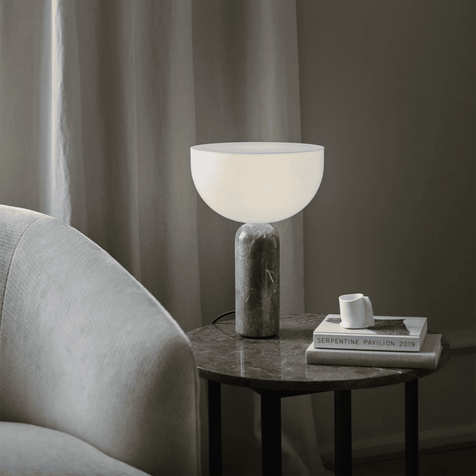 Table lamp on a side table next to a sofa with a neutral color scheme