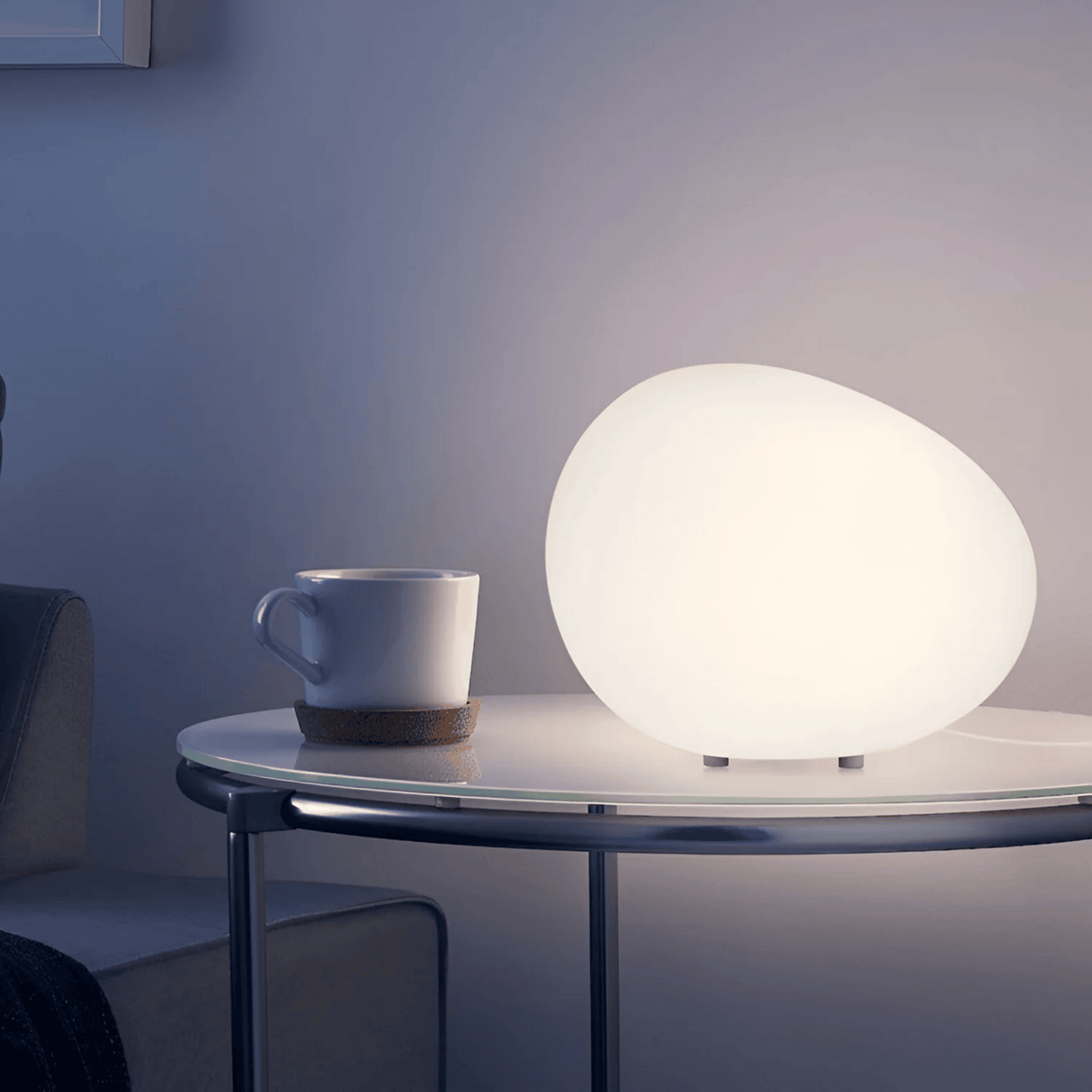 White spherical lamp and coffee cup on a table against a dark background