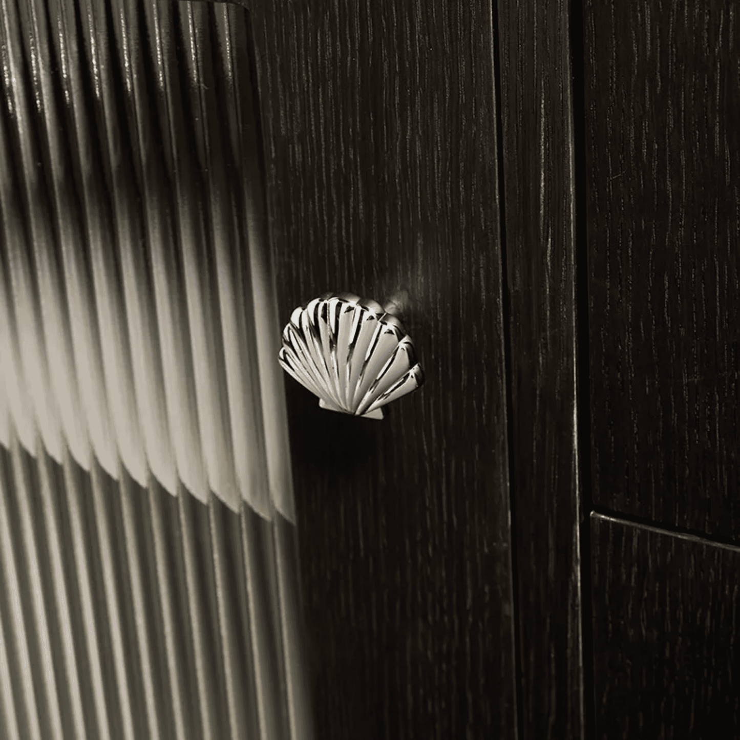 Close-up of a shell-shaped doorknob on a wooden door with a striped background.