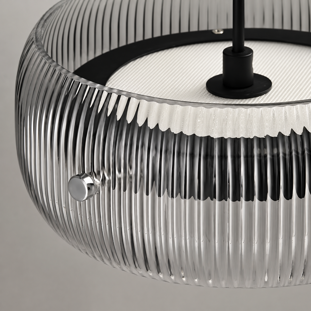 Close-up of a modern pendant light with a ribbed clear glass shade, black top band and central rod, and a white inner ring.