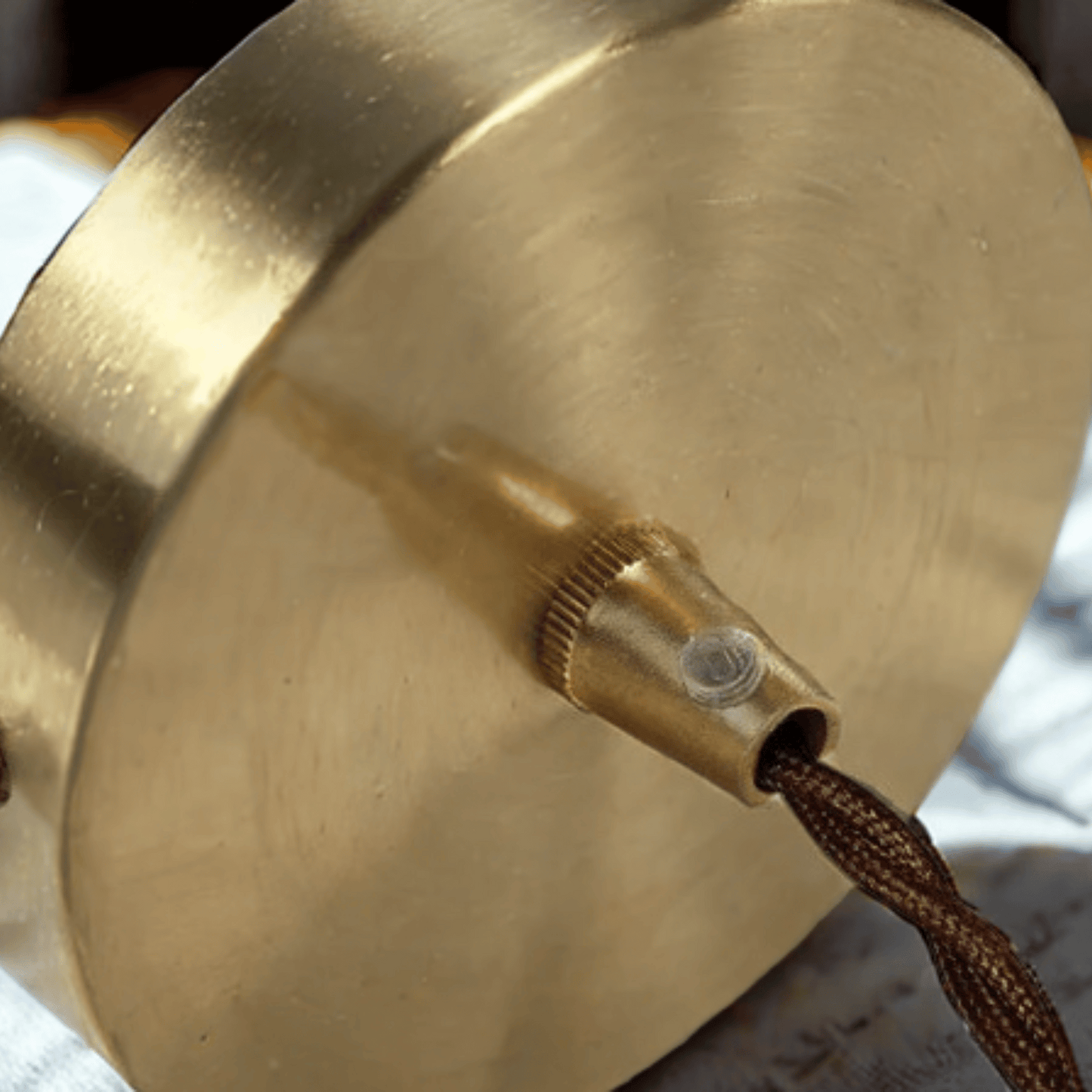 Close-up of a brass lampshade with a cord, on a blurred background