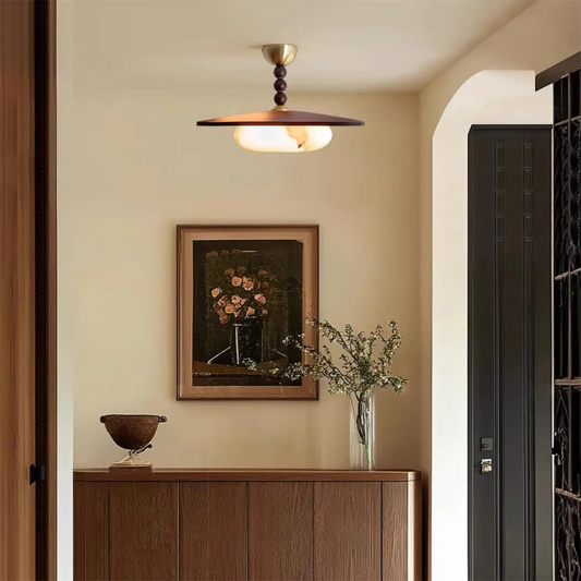 Decorative interior with a wooden cabinet, framed artwork, and a ceiling light fixture.