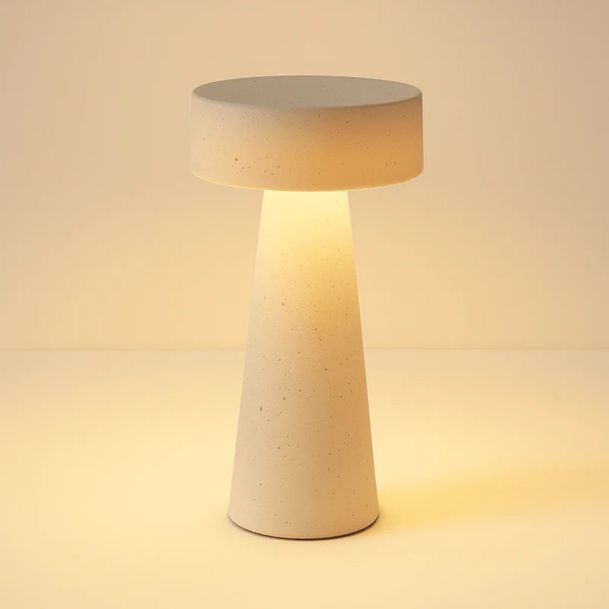 Concrete table lamp with a warm glow on a beige background