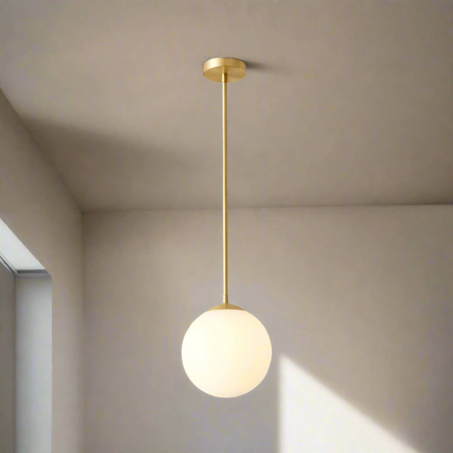 Gold pendant light with a white bulb on a white background