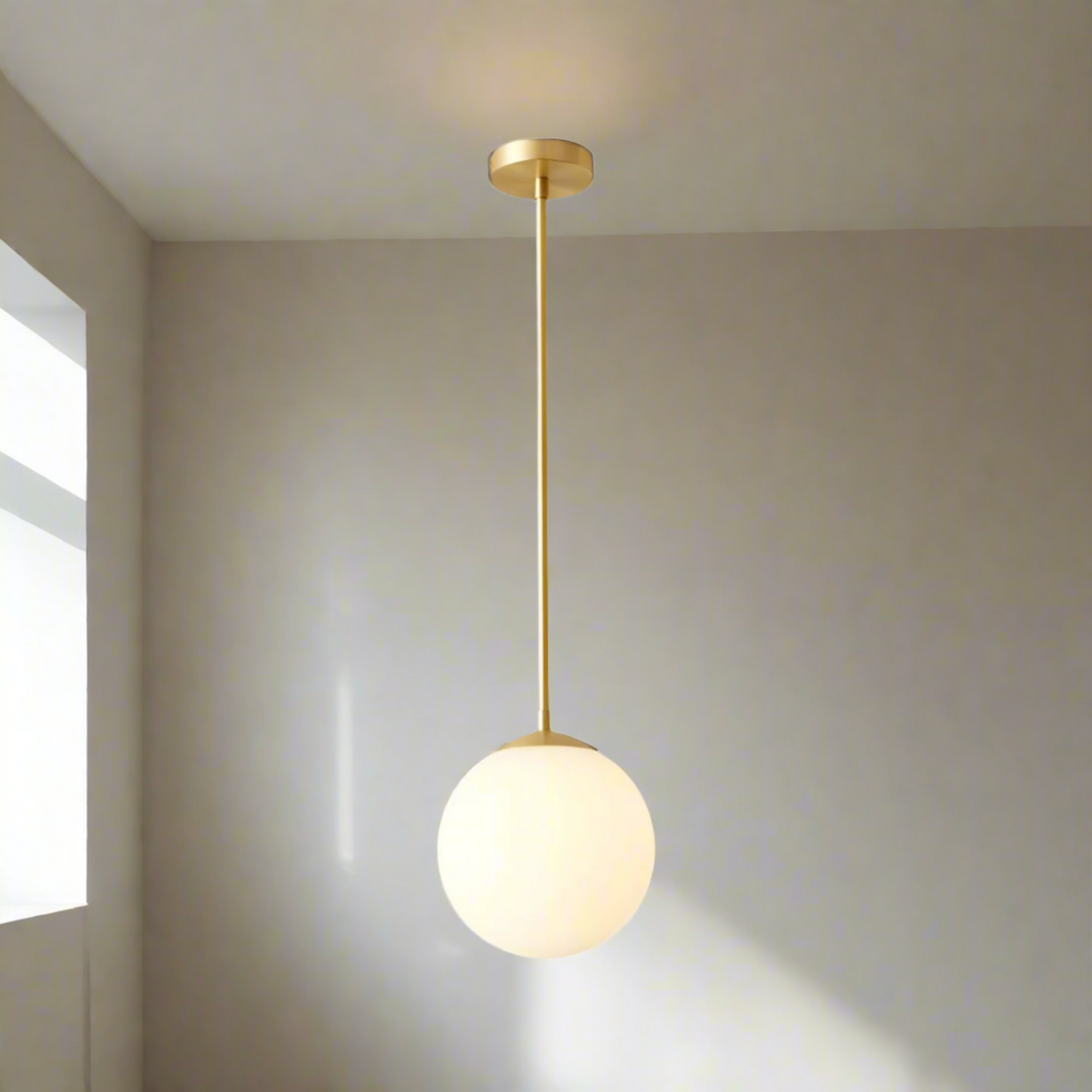 Gold pendant light with a white globe on a white background
