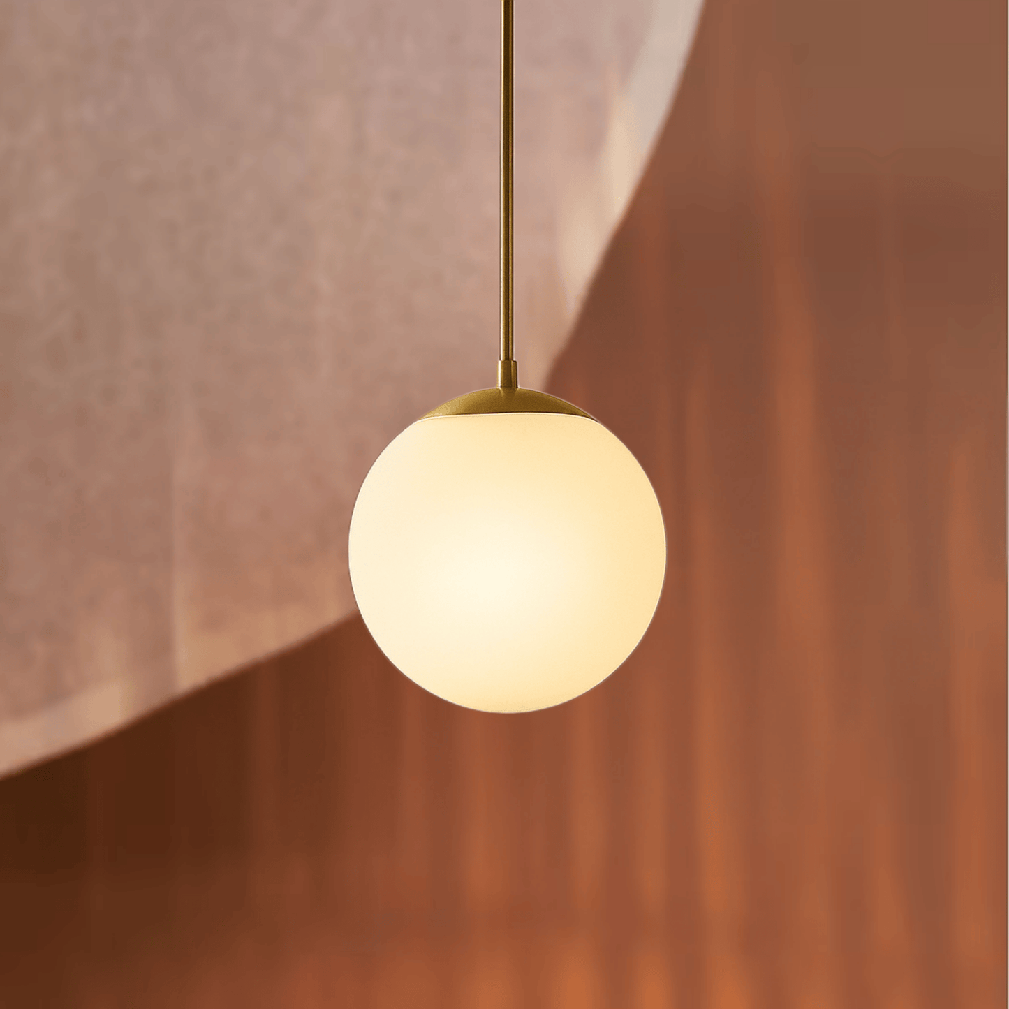 Spherical pendant light with gold fixture against a warm-toned wall.