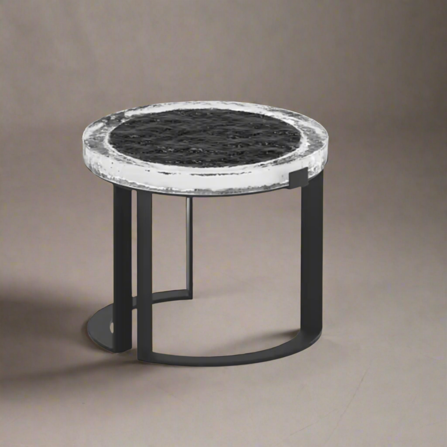 Small round table with black marble top and black metal base on a beige background