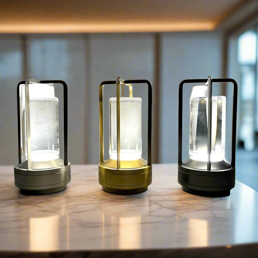 Three portable lanterns with different color finishes on a marble bench