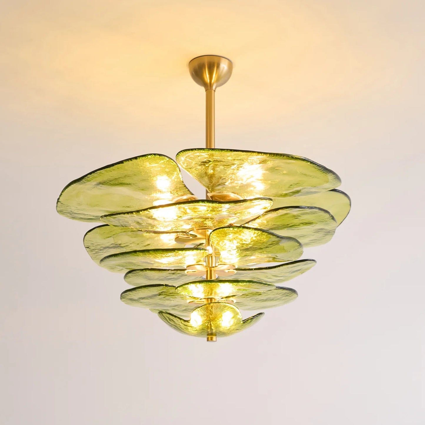 Chandelier with green glass shades and gold accents on a plain background