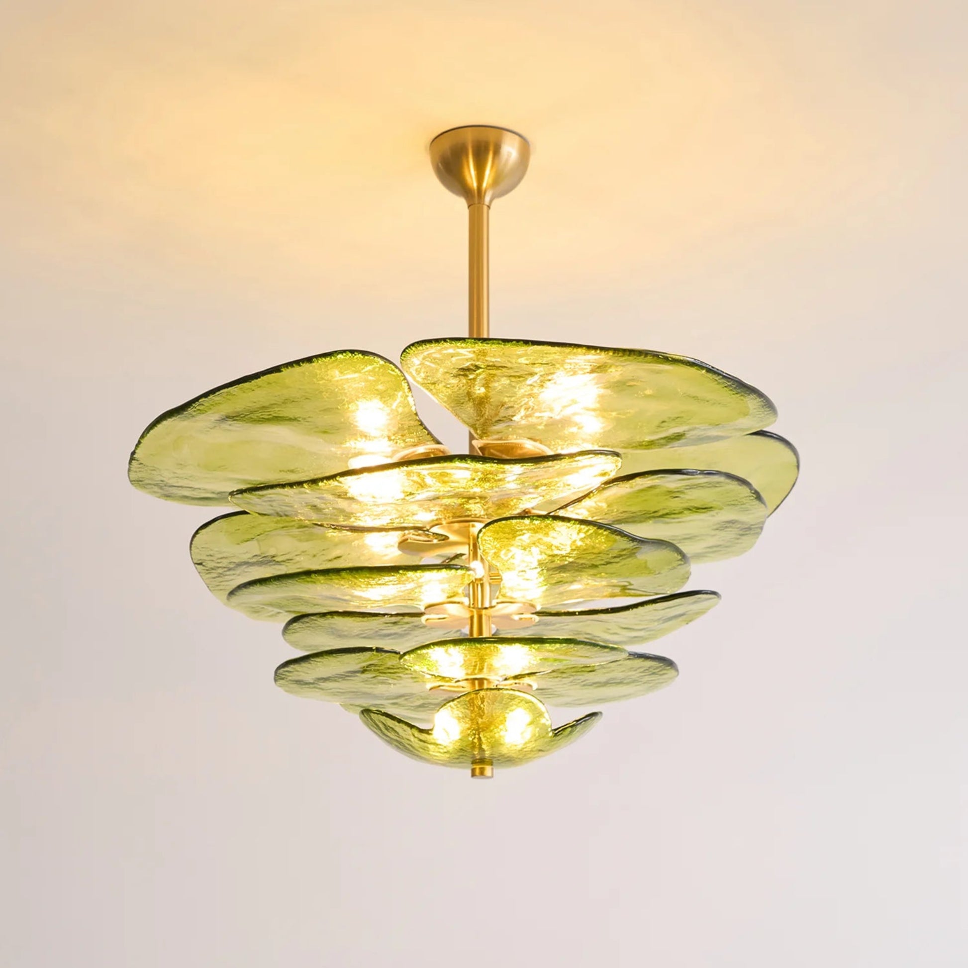 Chandelier with green glass shades and gold accents on a plain background