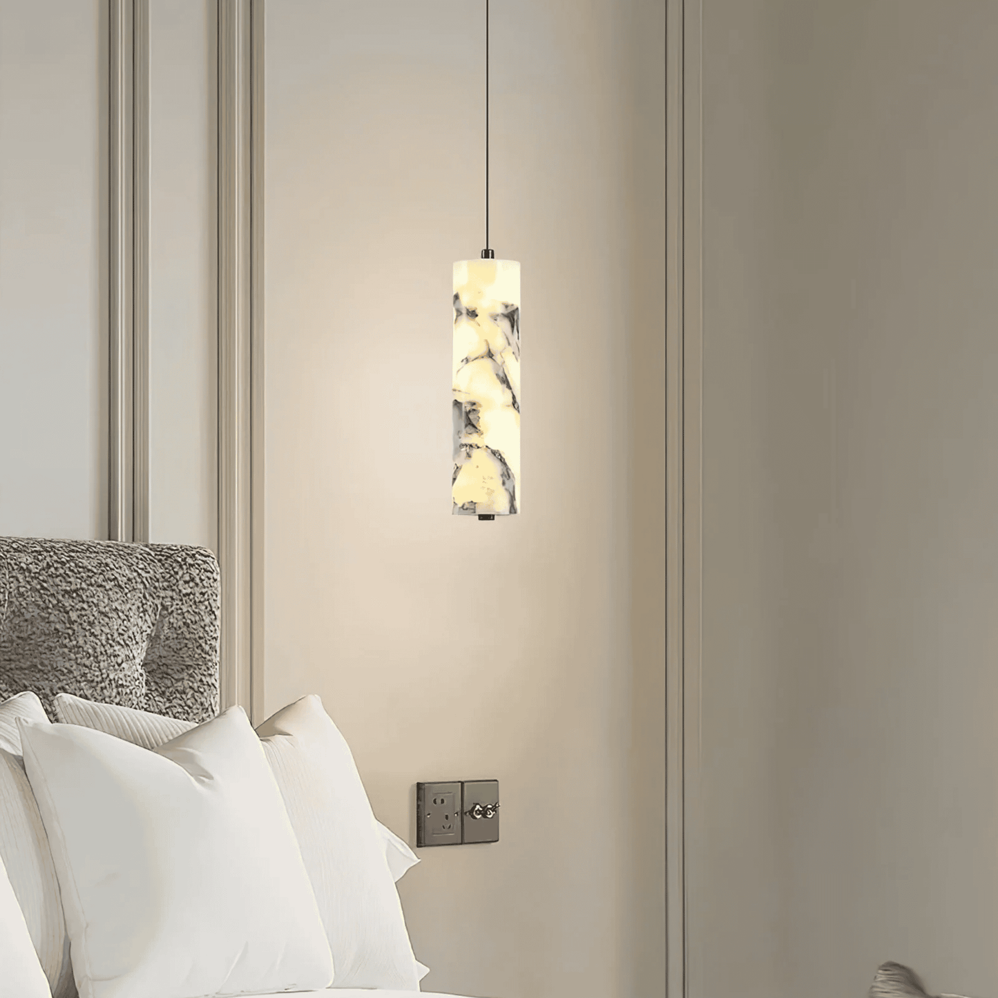 Modern pendant light fixture hanging above a bed in a bedroom setting.