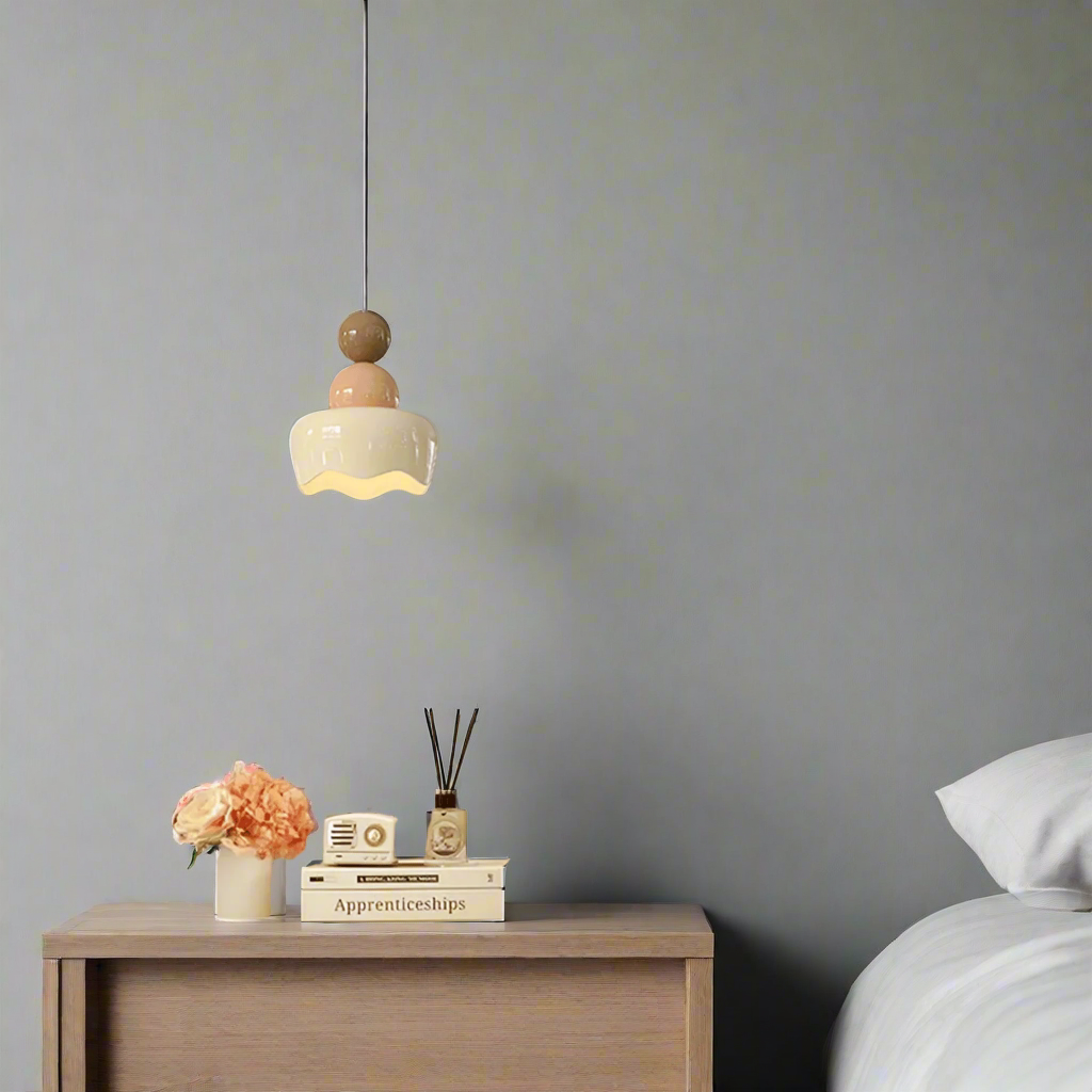 Neatly arranged bedroom with a lamp, books, and flowers on a nightstand.