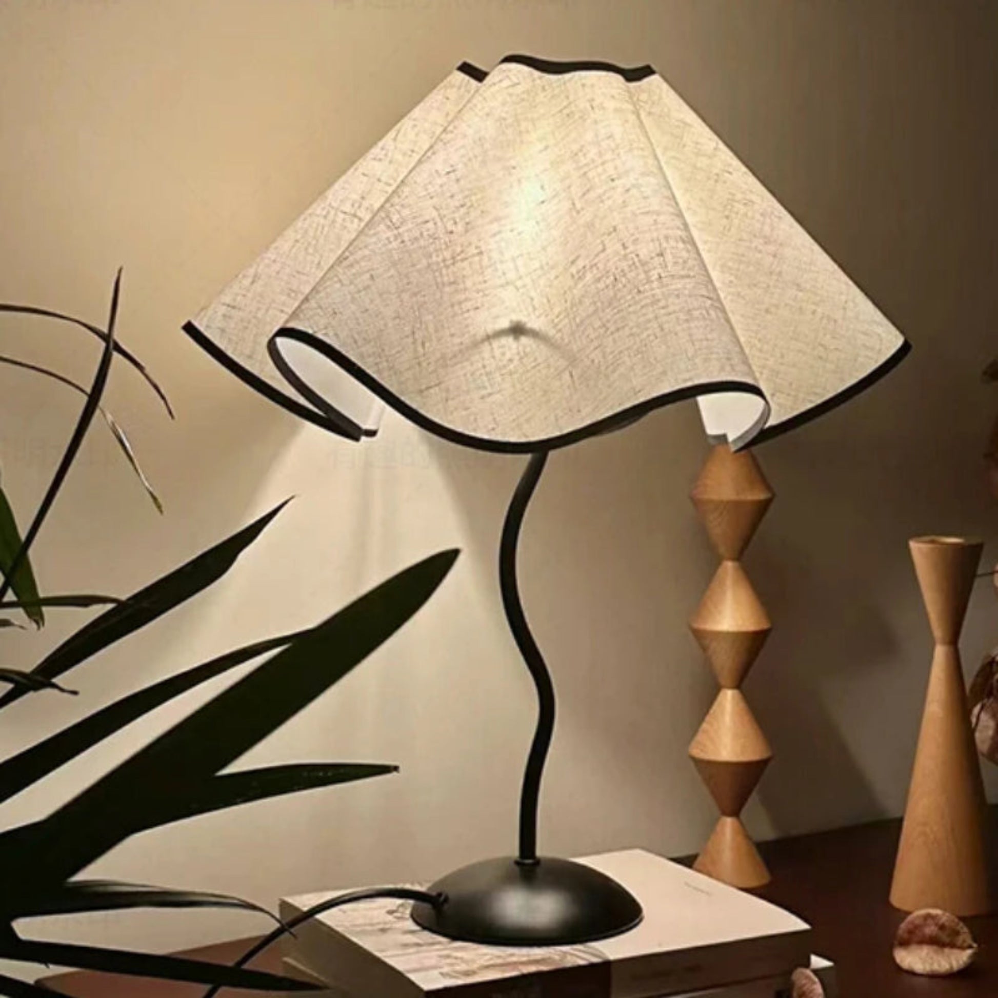 Table lamp with a white textured shade on a wooden surface, surrounded by decorative items.