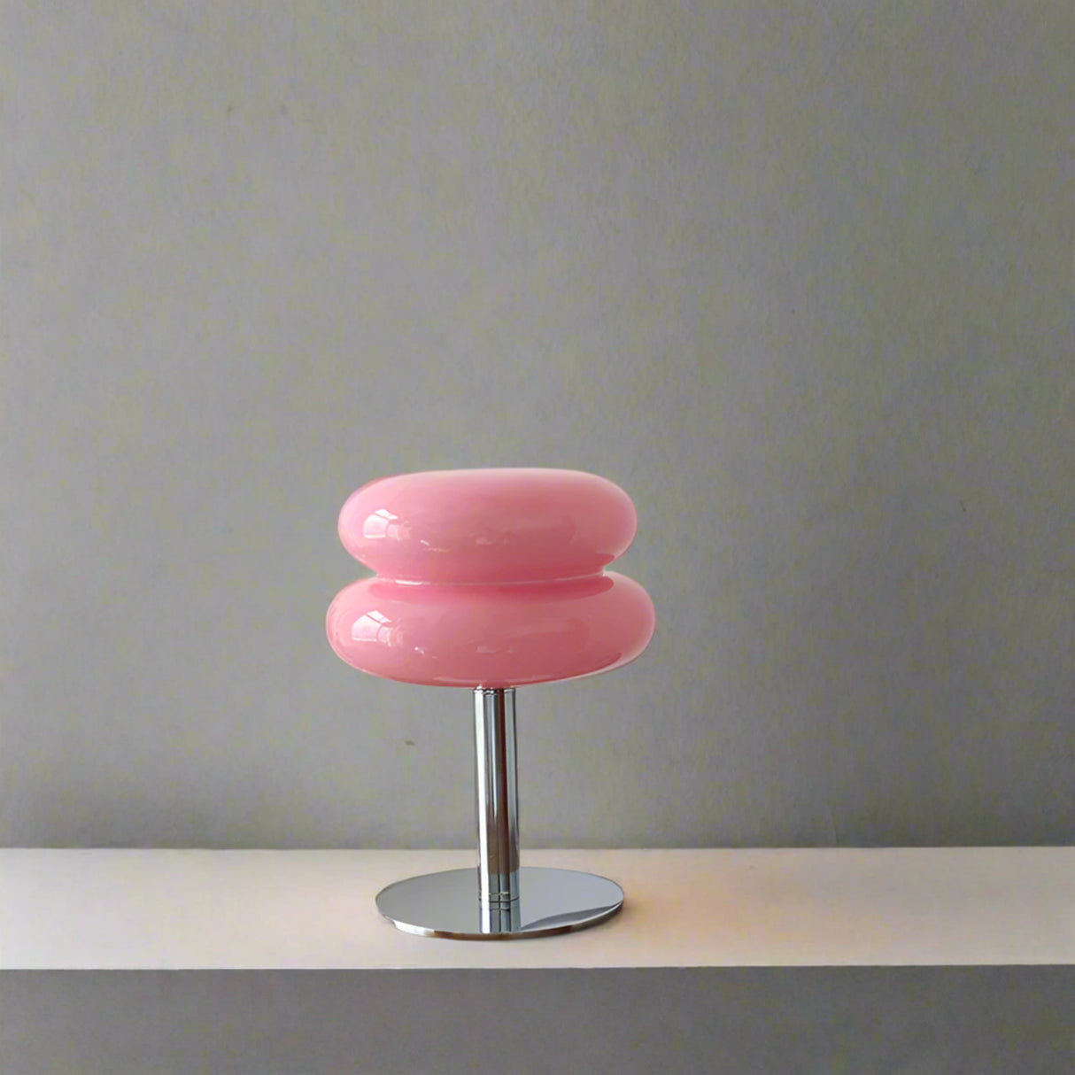 Pink stool on a wooden surface with decorative items against a white wall
