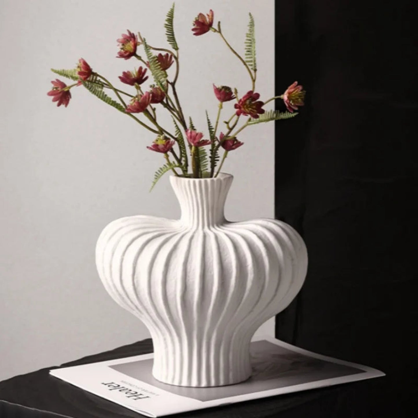White textured vase with floral arrangement on a dark surface
