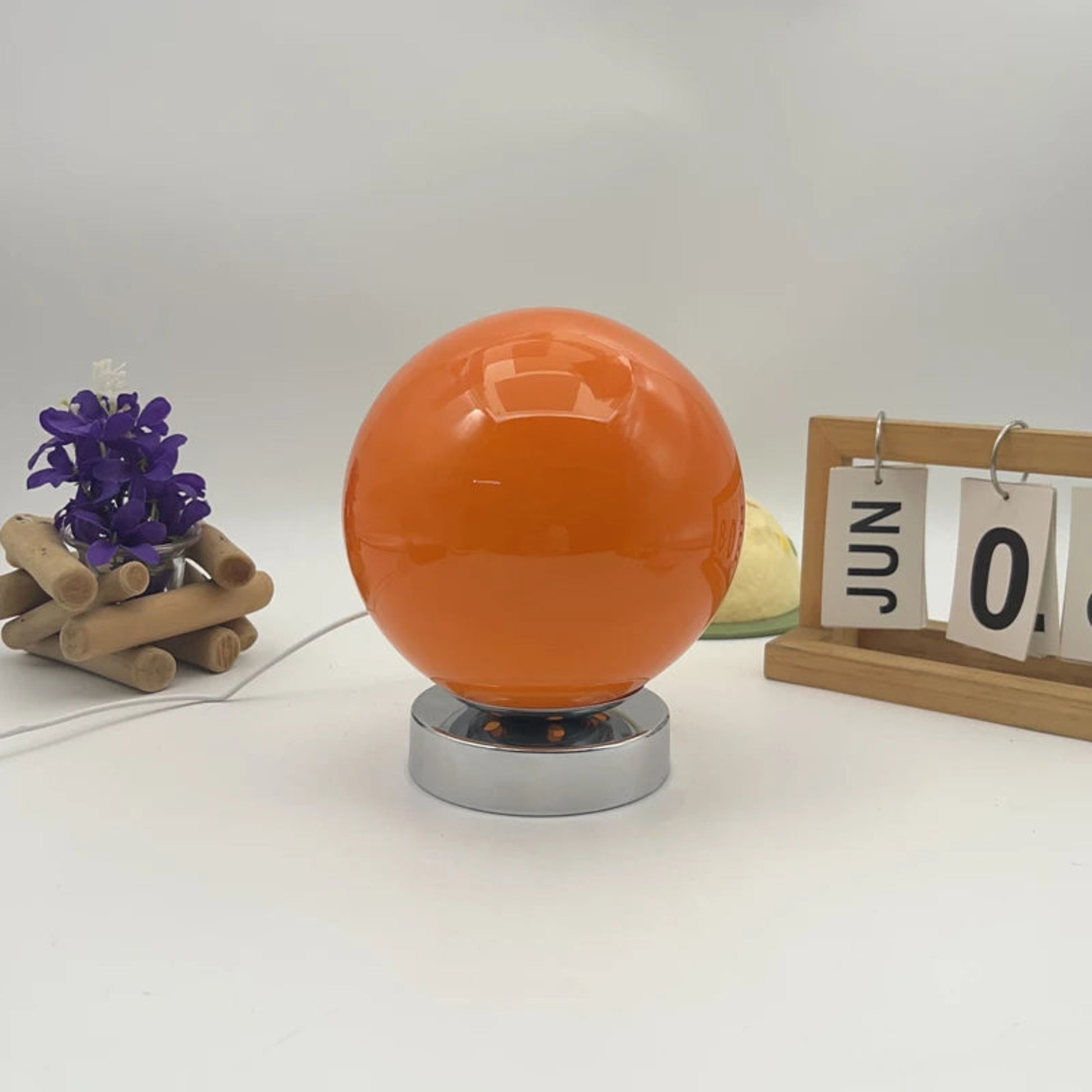 Orange spherical object on a white surface with decorative items.
