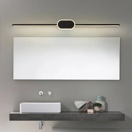 Modern bathroom setup with a large mirror, light fixture, sink, and decorative items.