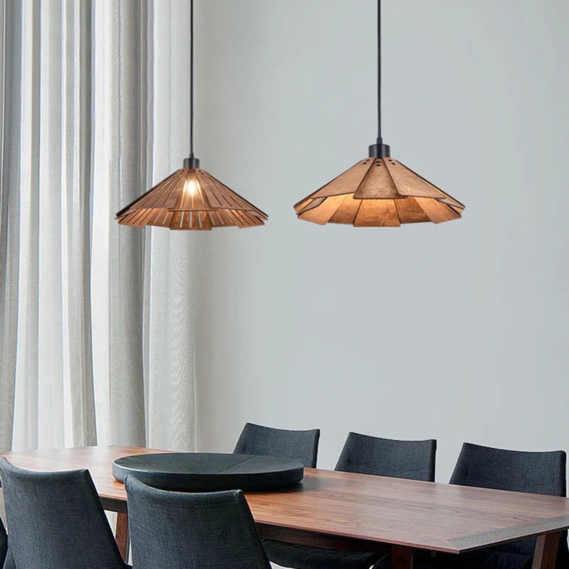 Two pendant lights hanging above a dining table with chairs in a room.