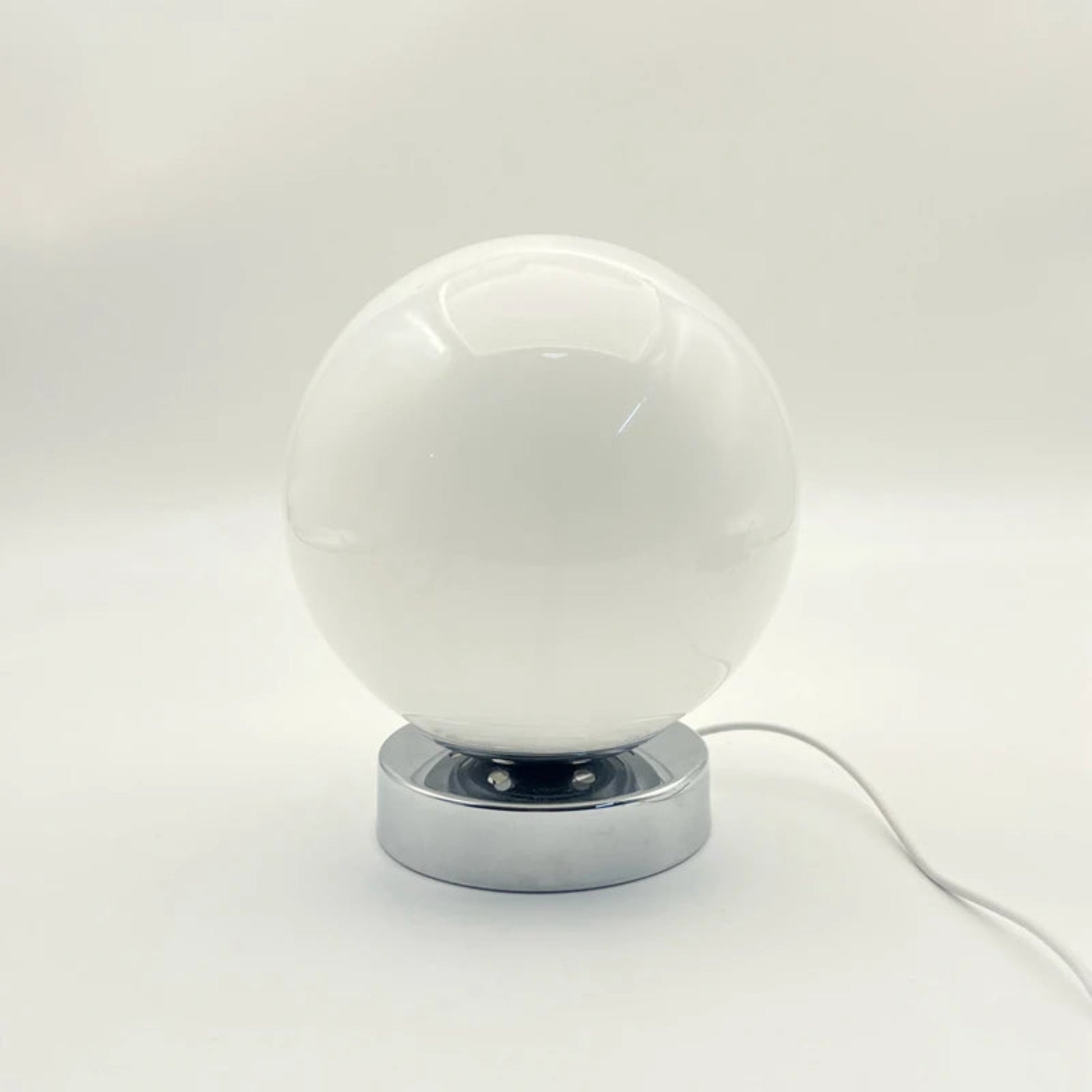 White spherical lamp with a chrome base on a light gray background