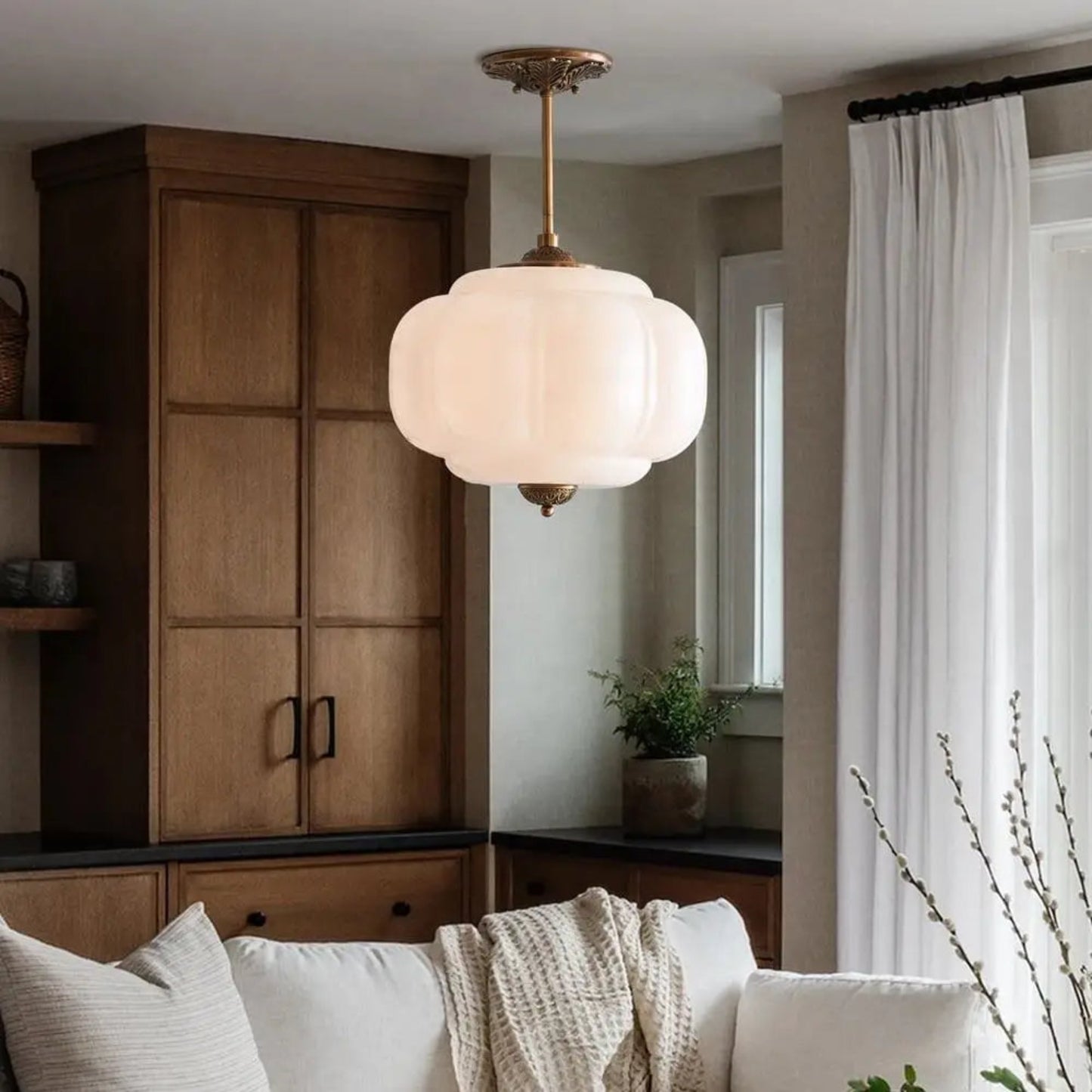 Living room with a ceiling light fixture, wooden cabinet, and white sofa.
