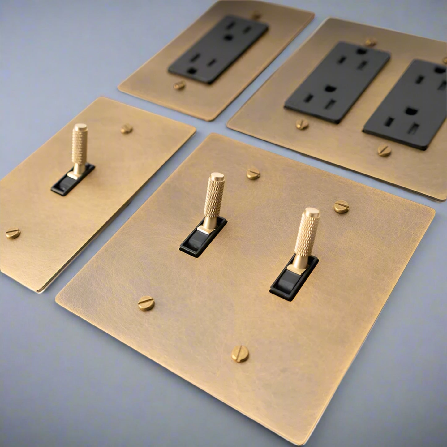 Brass light switch plates with black outlets on a white background,