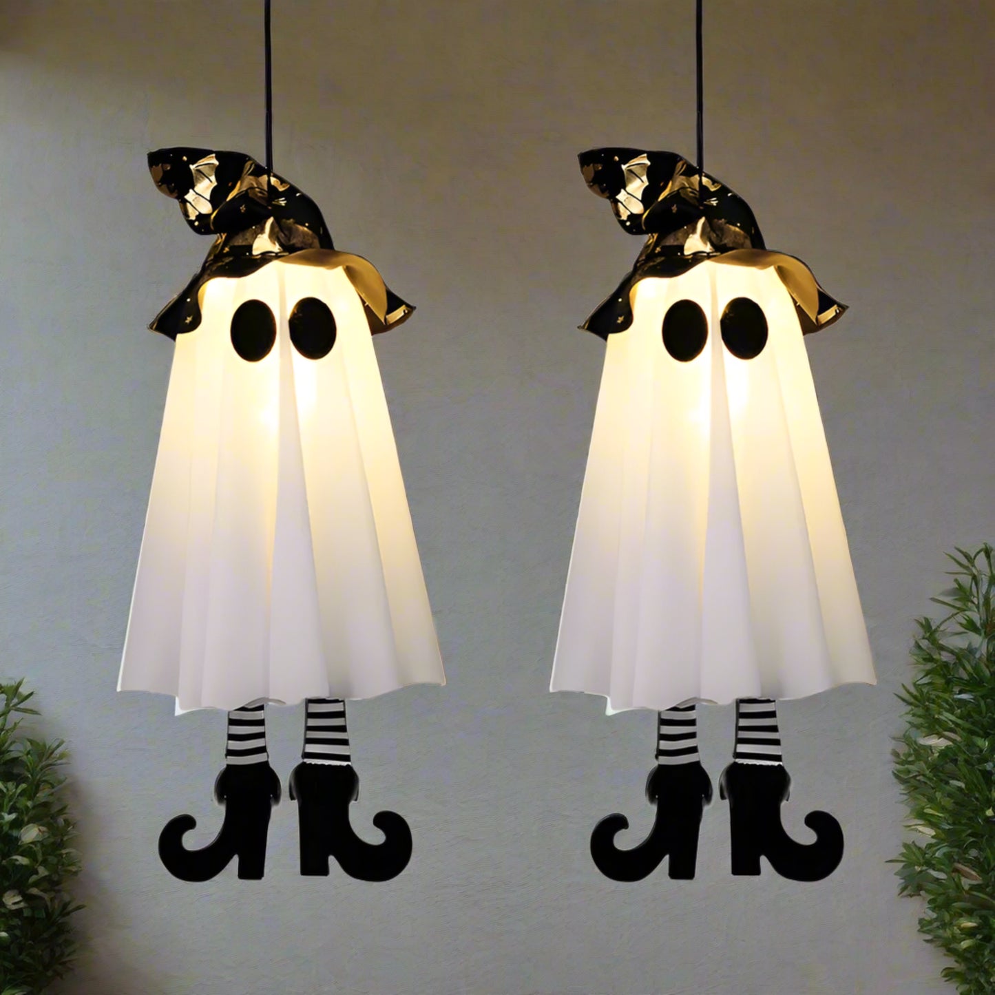 Two Halloween ghost decorations with black hats and striped legs on a white background