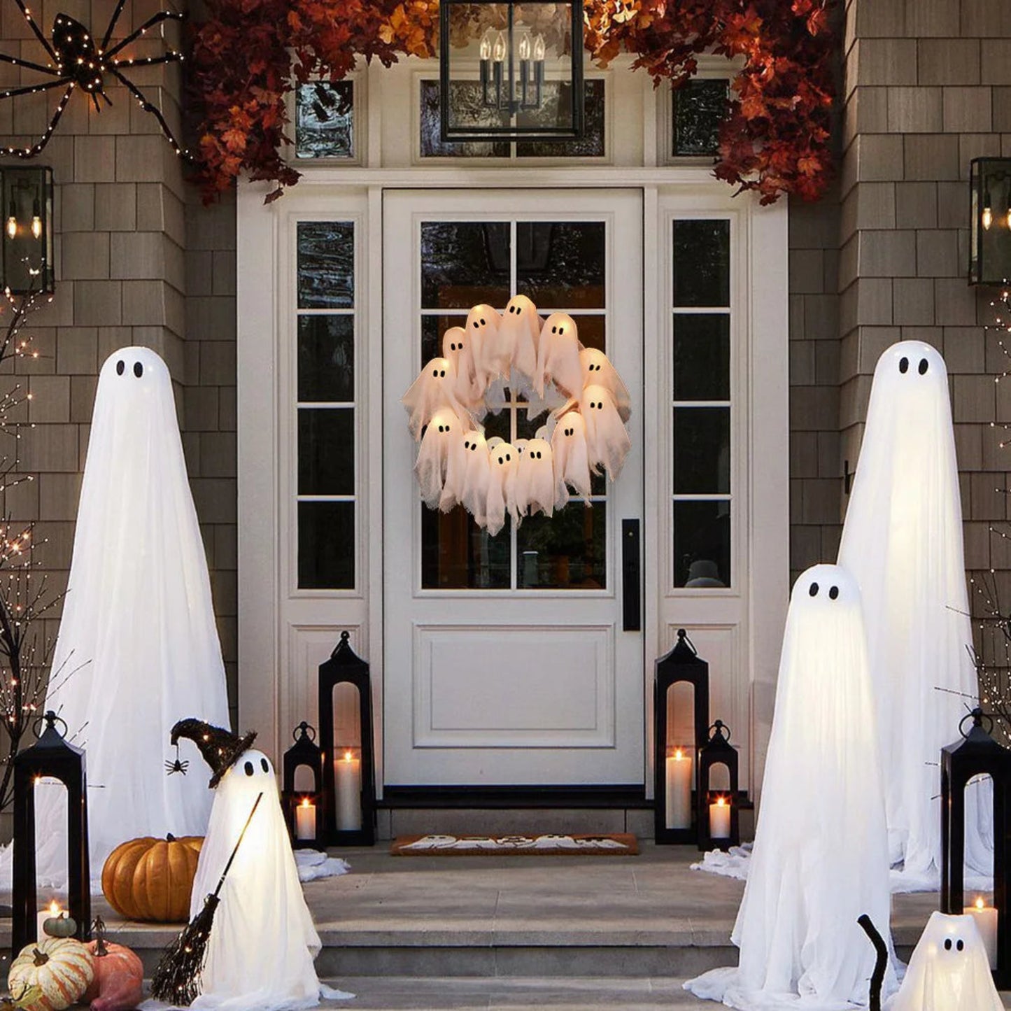 Halloween decorations including ghosts, pumpkins, and a wreath with lights on a door.
