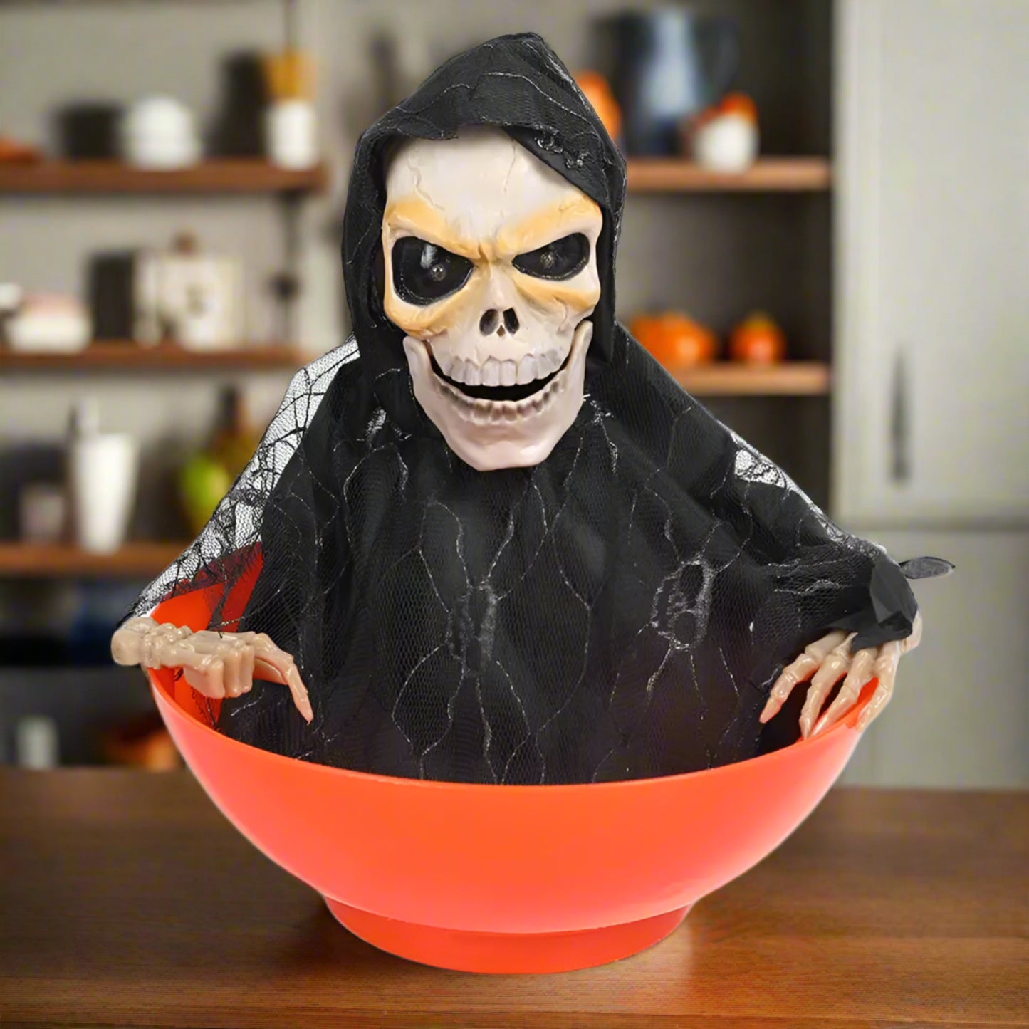 Skeleton figure in a black hooded outfit inside an orange bowl on a white background
