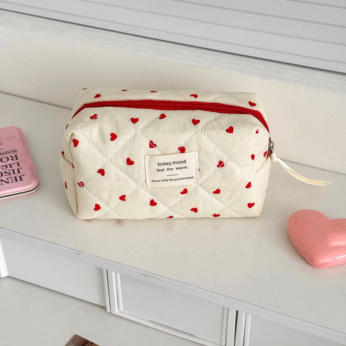 White pouch with red heart patterns on a white surface