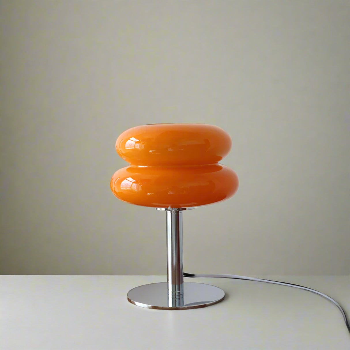 Orange table lamp on a wooden surface with decorative items in the background