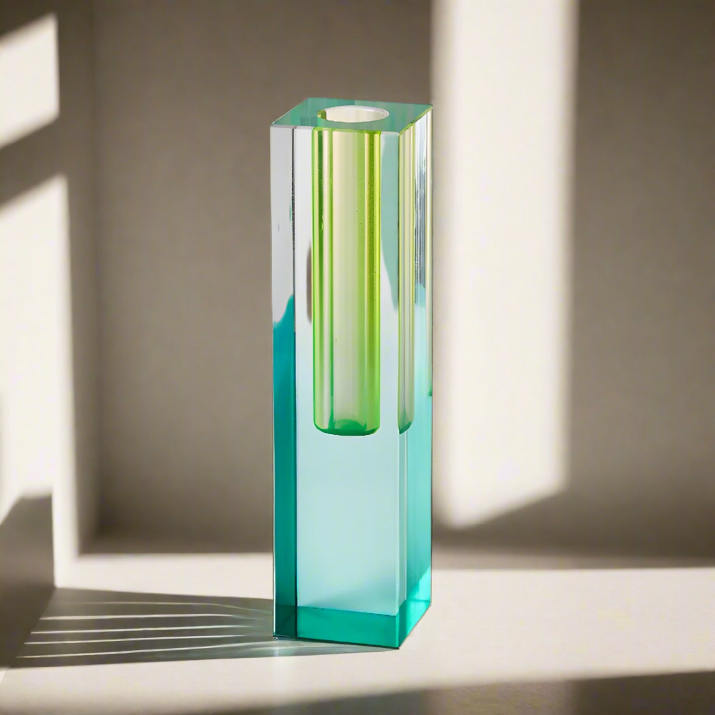 Tall, hexagonal glass candle holder with green and blue gradient on a light gray background