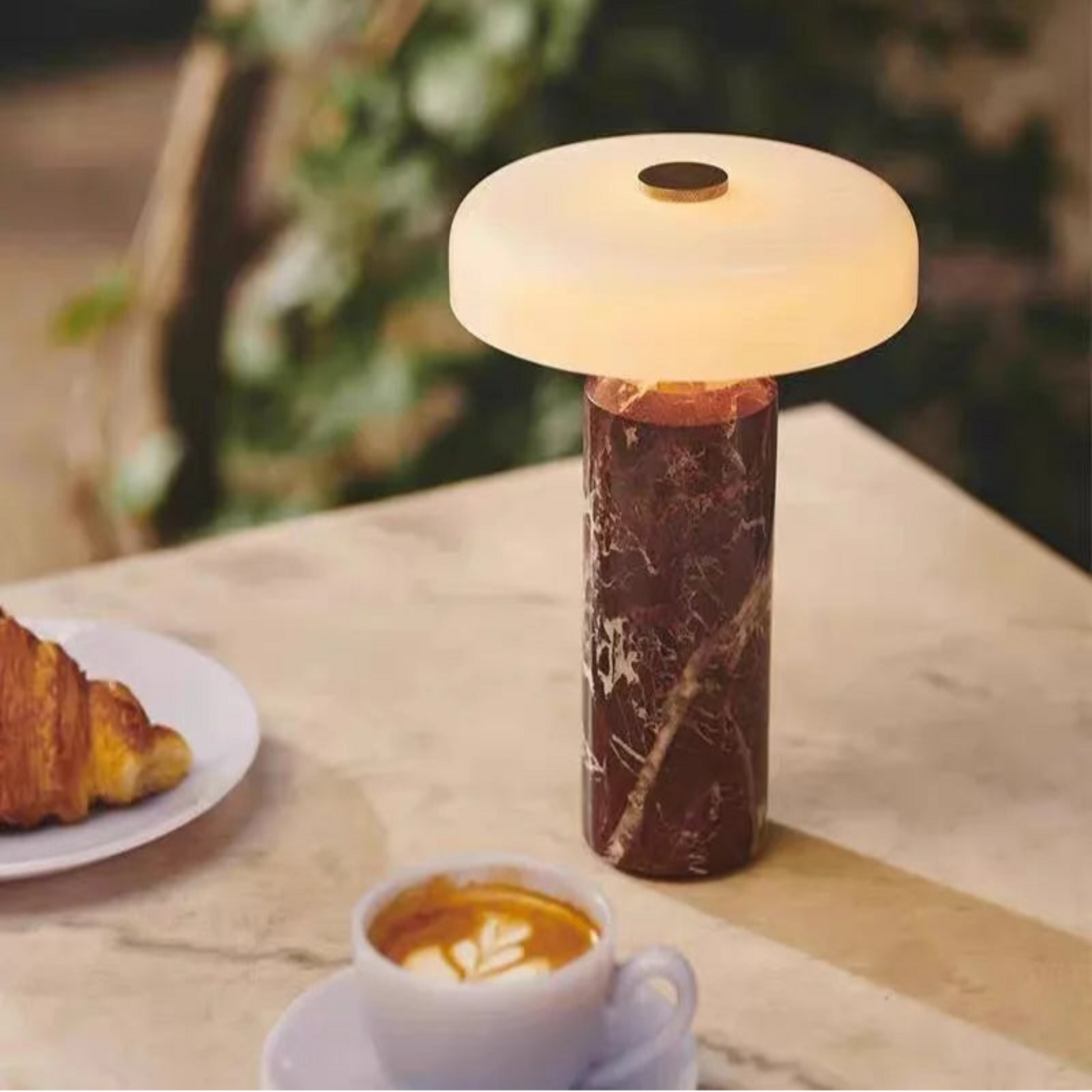 Marble-patterned table lamp on a wooden surface with a croissant and coffee cup.
