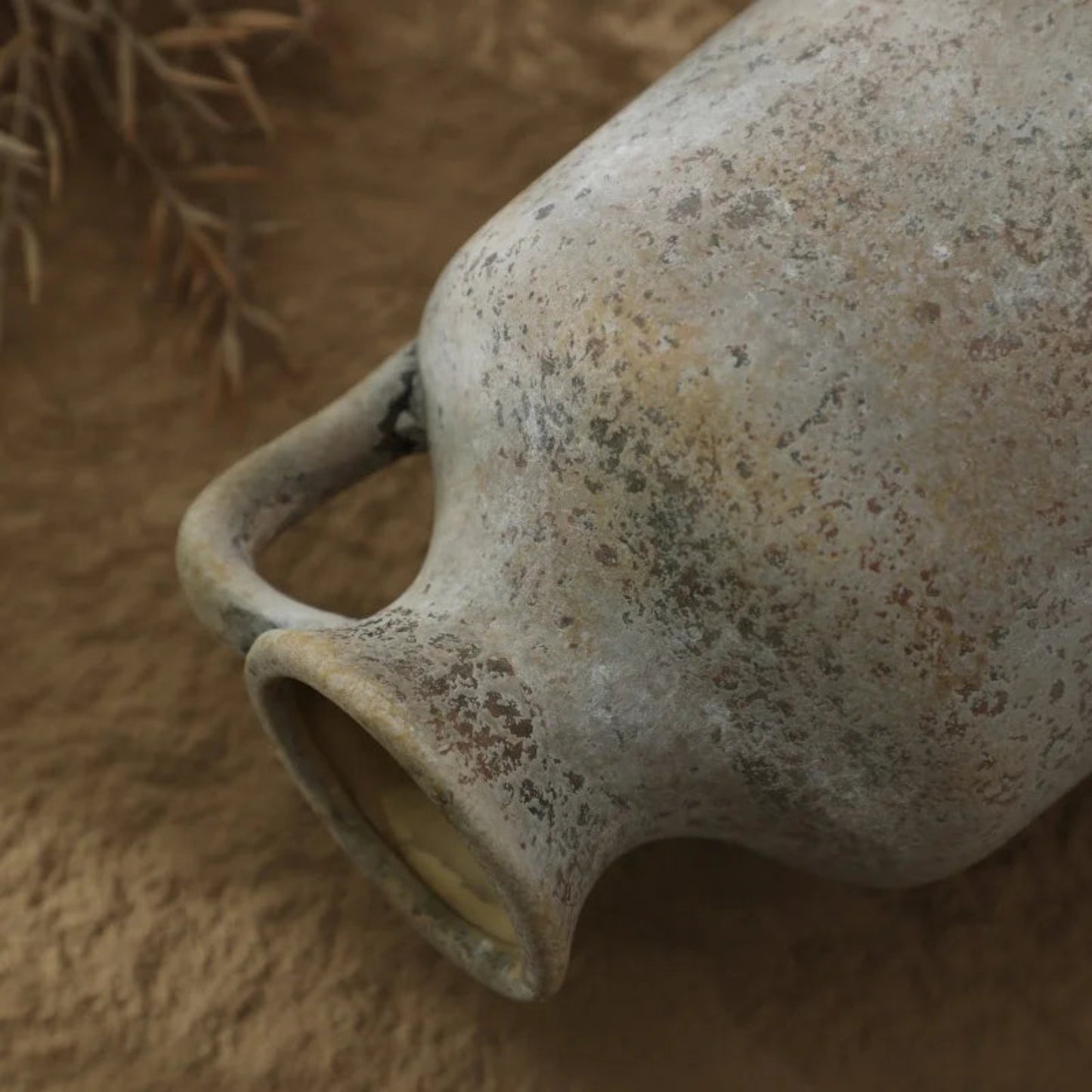 Close-up of a rustic ceramic vase on a textured surface