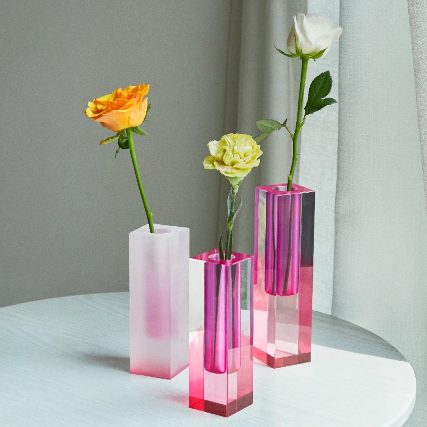 Three gradient vases with flowers on a light surface