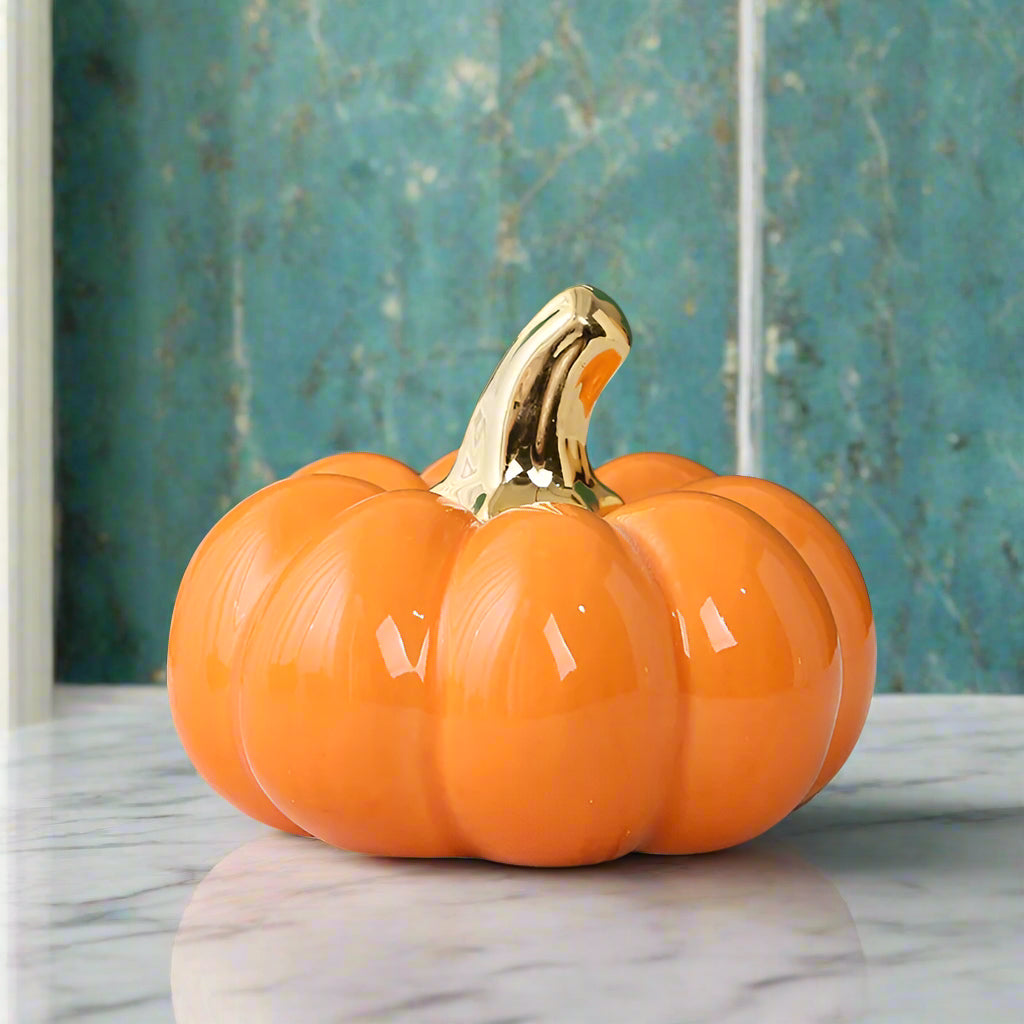 Decorative pumpkin with a gold stem on a marble surface