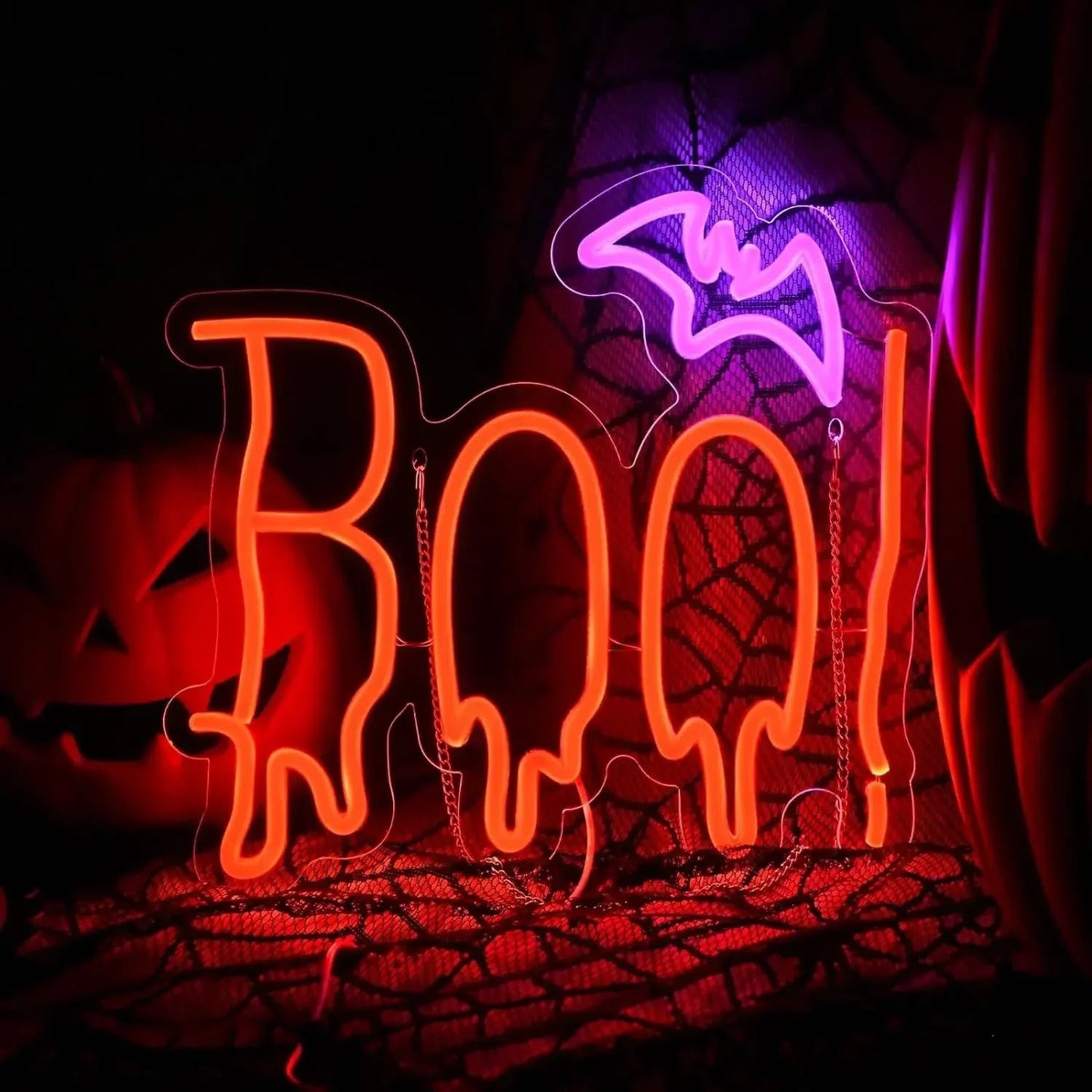 Neon 'BOO!' sign with a purple bat and spider web on a dark background