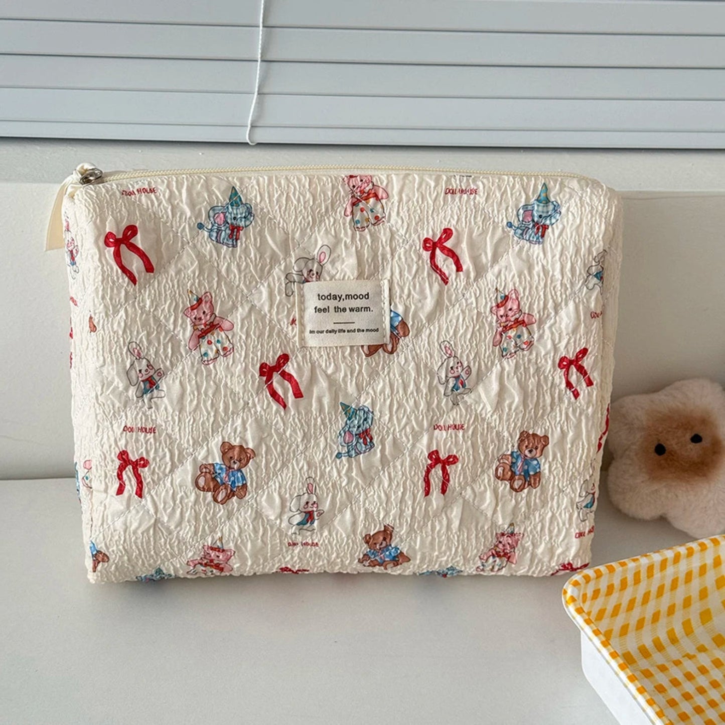 Fabric pouch with teddy bear and bow pattern on a plain background